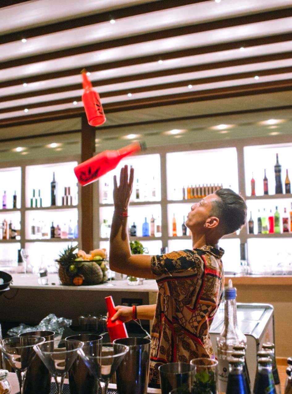 Un camarero hace malabares con botellas en un bar.