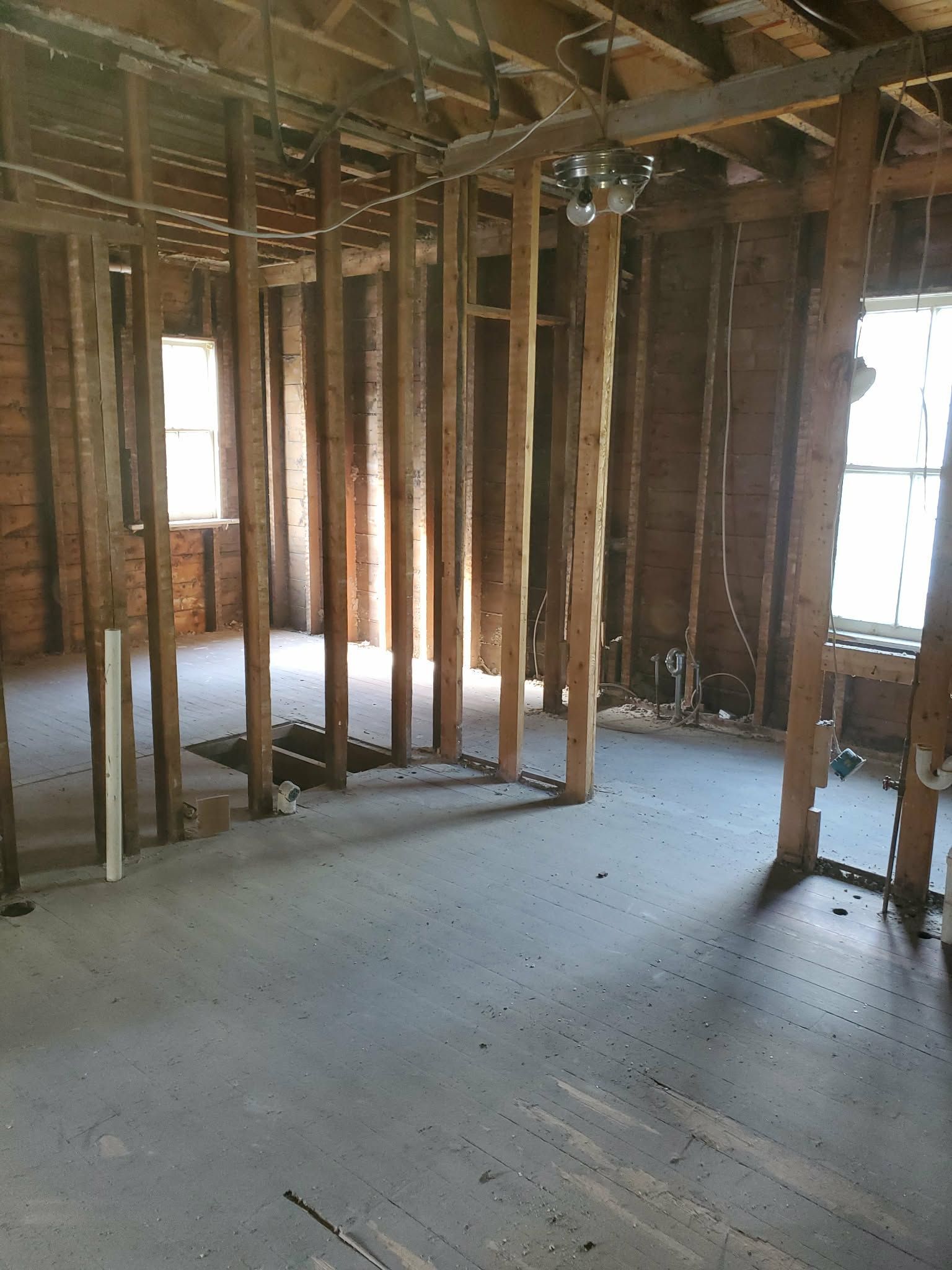 Interior of a house under construction with exposed wooden framing and unfinished concrete floor