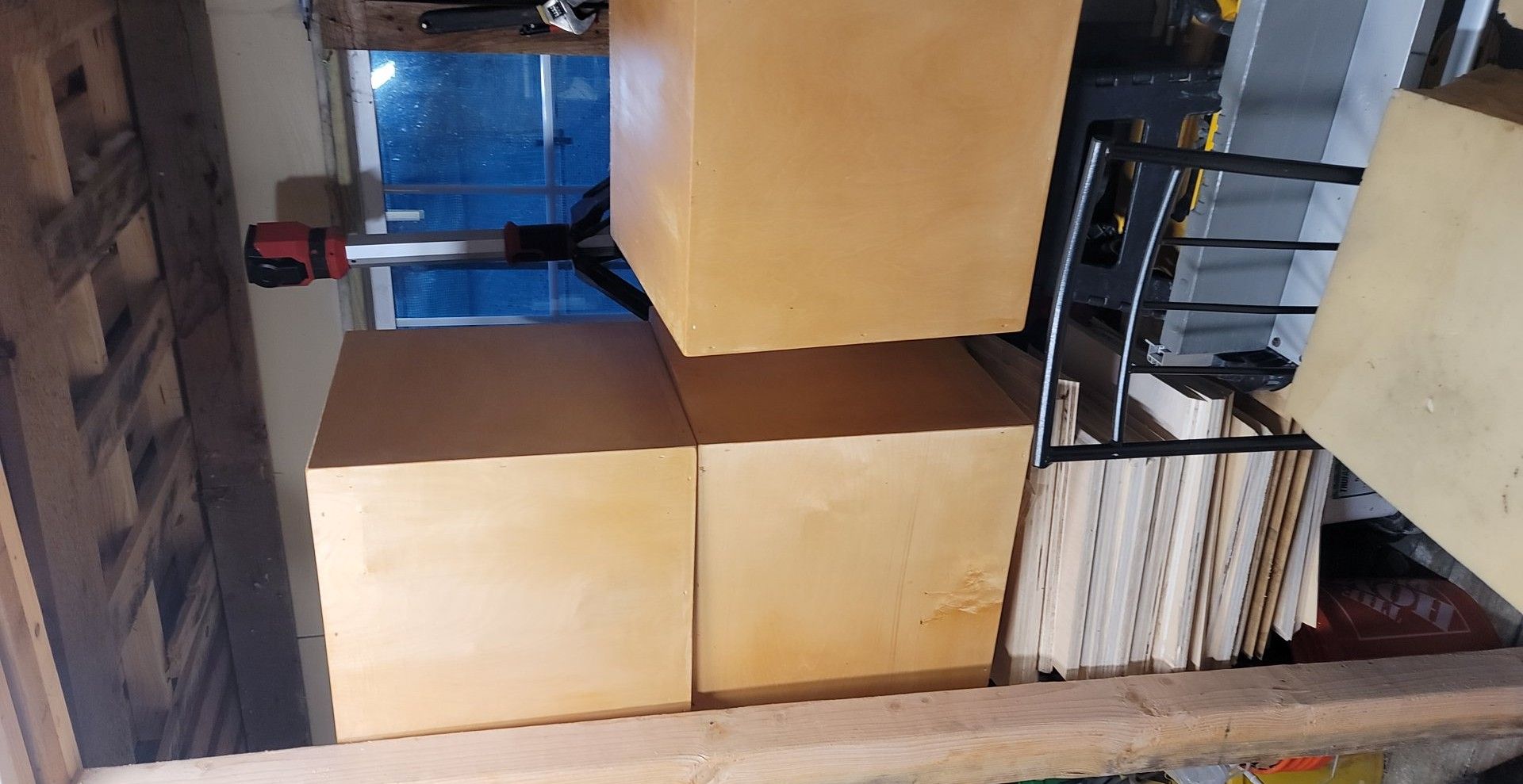 Stacked cardboard boxes in a warehouse aisle beside a metal shelving unit.