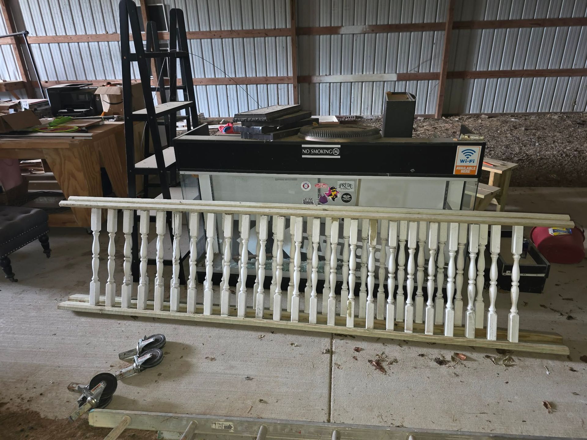 White radiator with black top panel lying in a barn workshop, with tools and equipment around it.