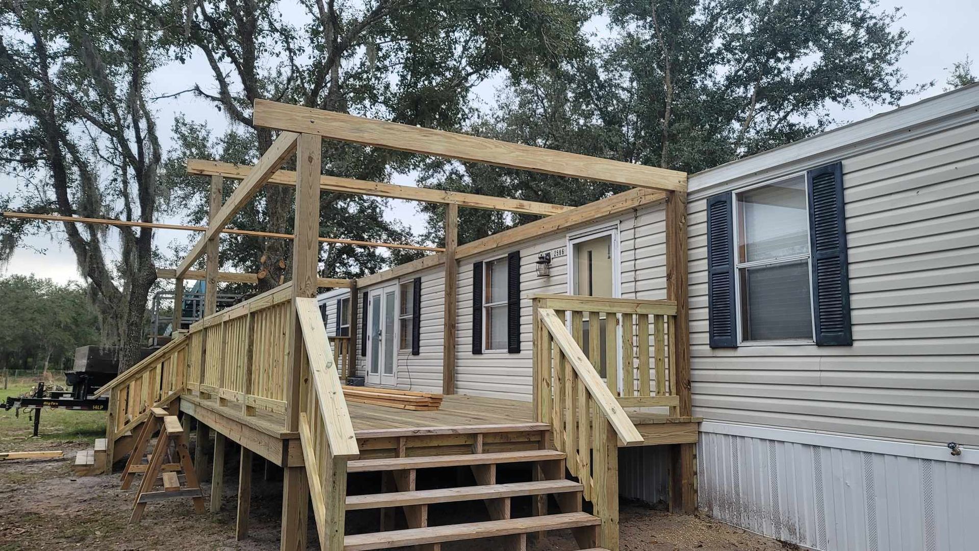 Wooden wheelchair ramp and stairs beside a beige mobile home under construction