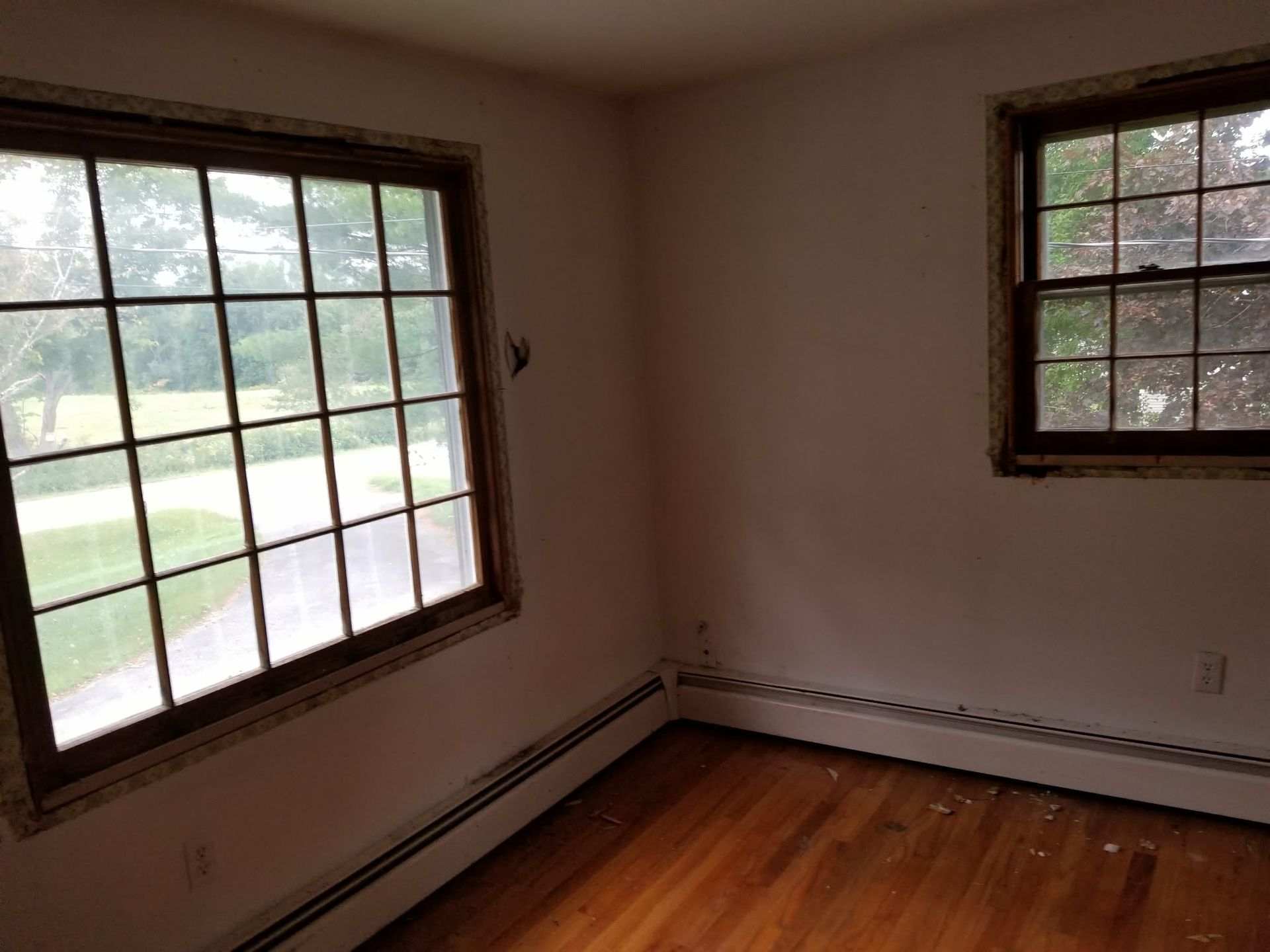 Empty room with hardwood floor and two windows letting in daylight