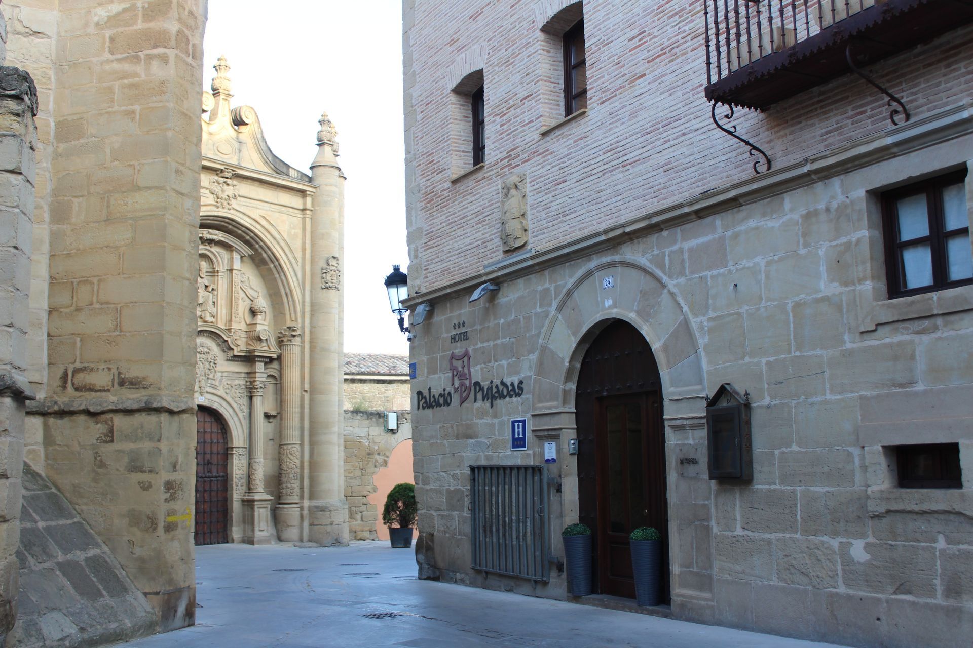 Calle estrecha empedrada junto a la entrada ornamentada de una catedral en un casco antiguo.
