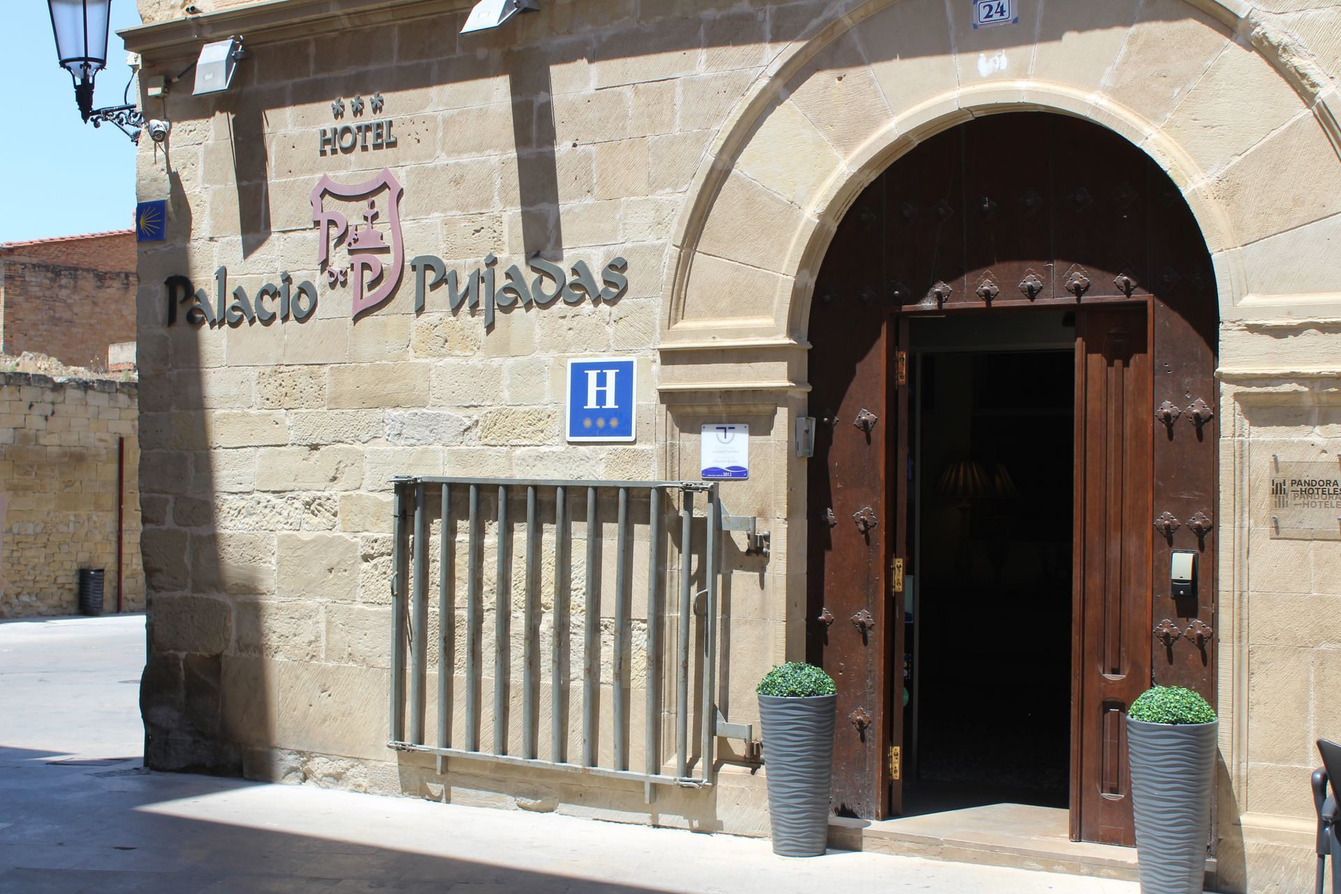Entrada de piedra del hotel con arco, puerta de madera y letrero “Palacio de Pizarro”.