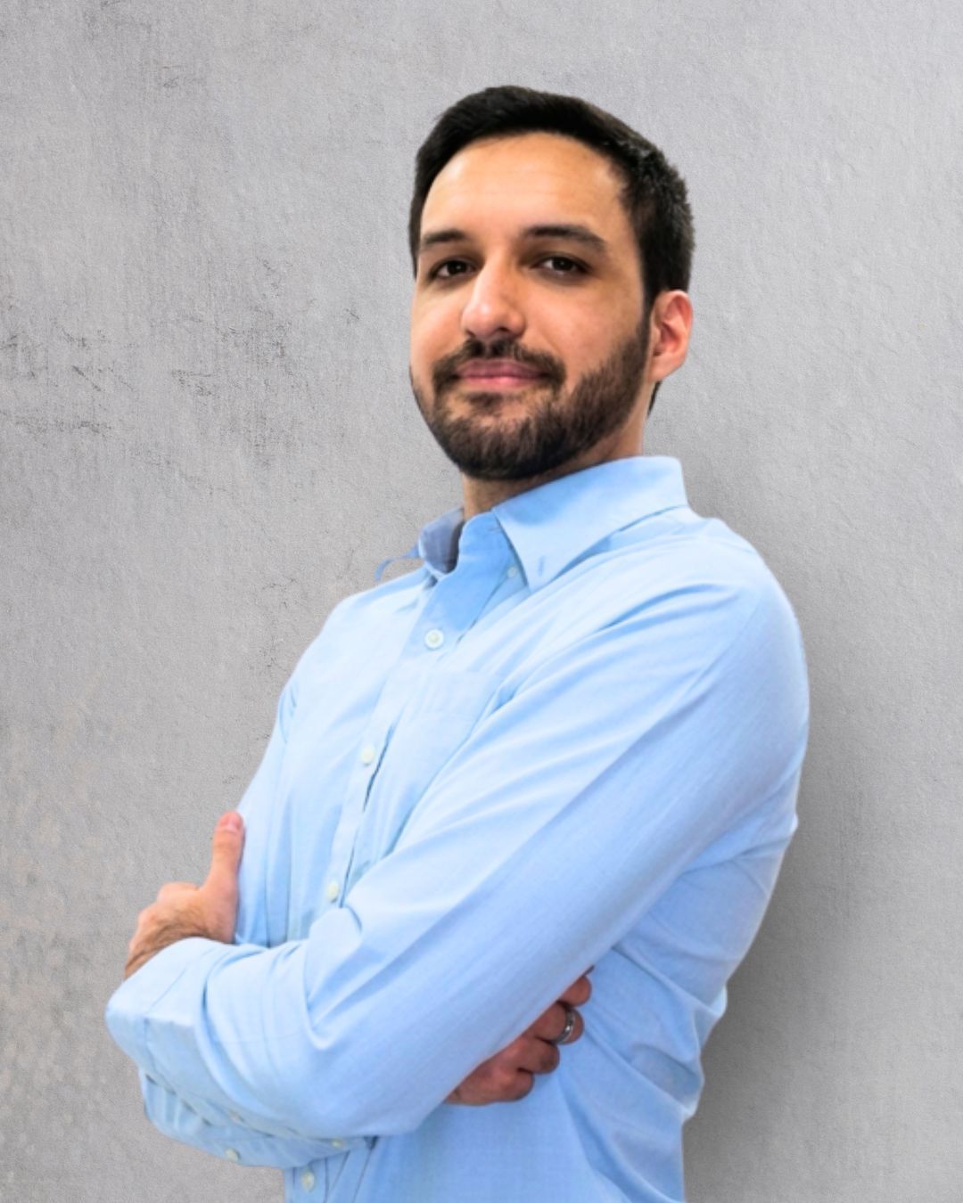 Retrato de un hombre con una camiseta azul claro sobre un fondo gris liso.