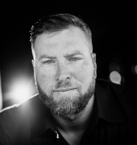 Black-and-white close-up portrait of a bearded man against a dark background