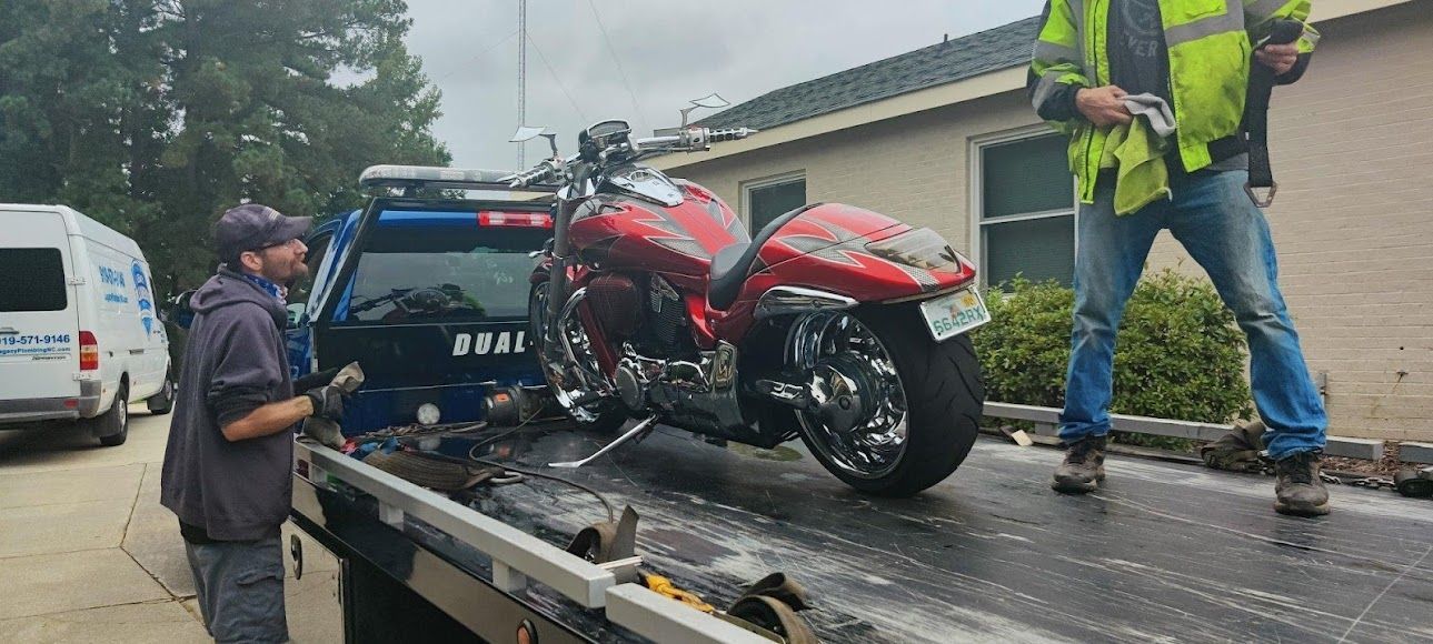 Motorcycle being loaded onto a tow truck beside a police vehicle on a wet road