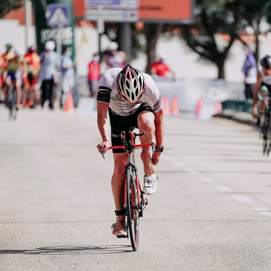 Cyclist in white helmet sprinting hard toward the finish line on a city street