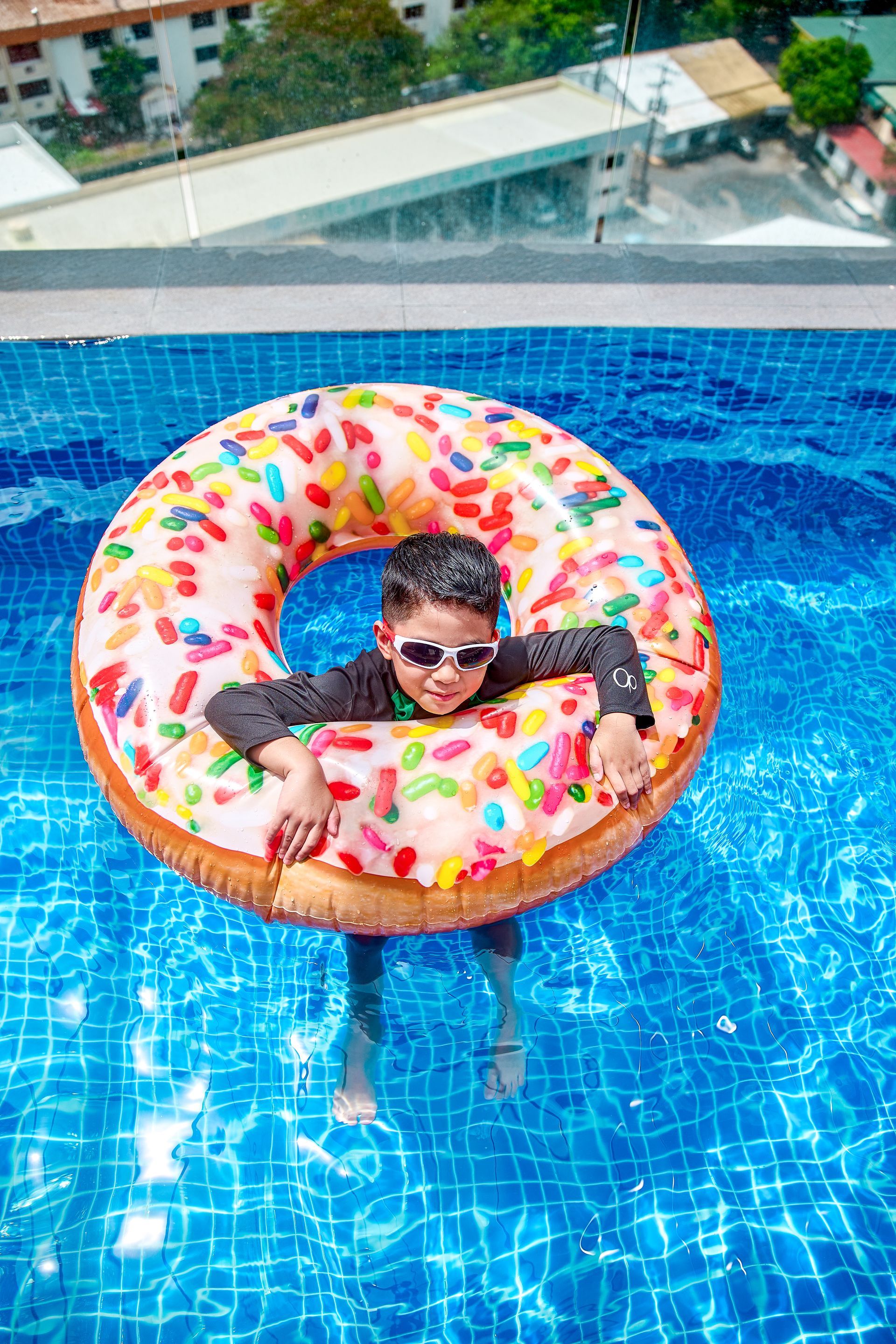 Boy with sunglasses on donut pool float at Aurora Subic rooftop pool
