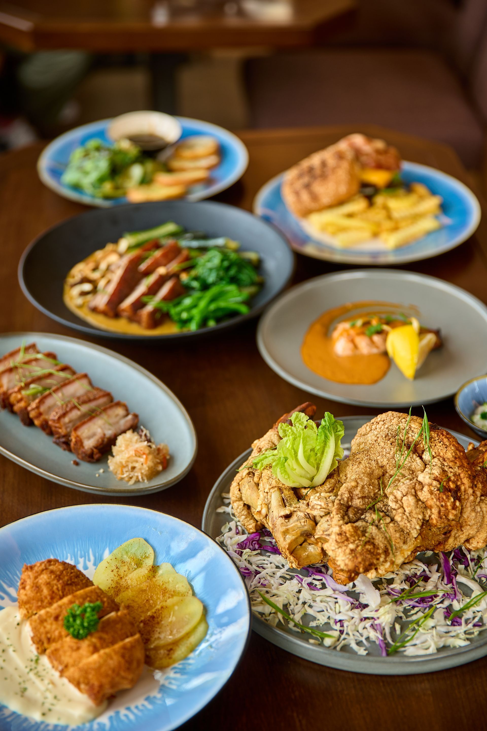 Various colorful dishes on plates on a brown wooden table.