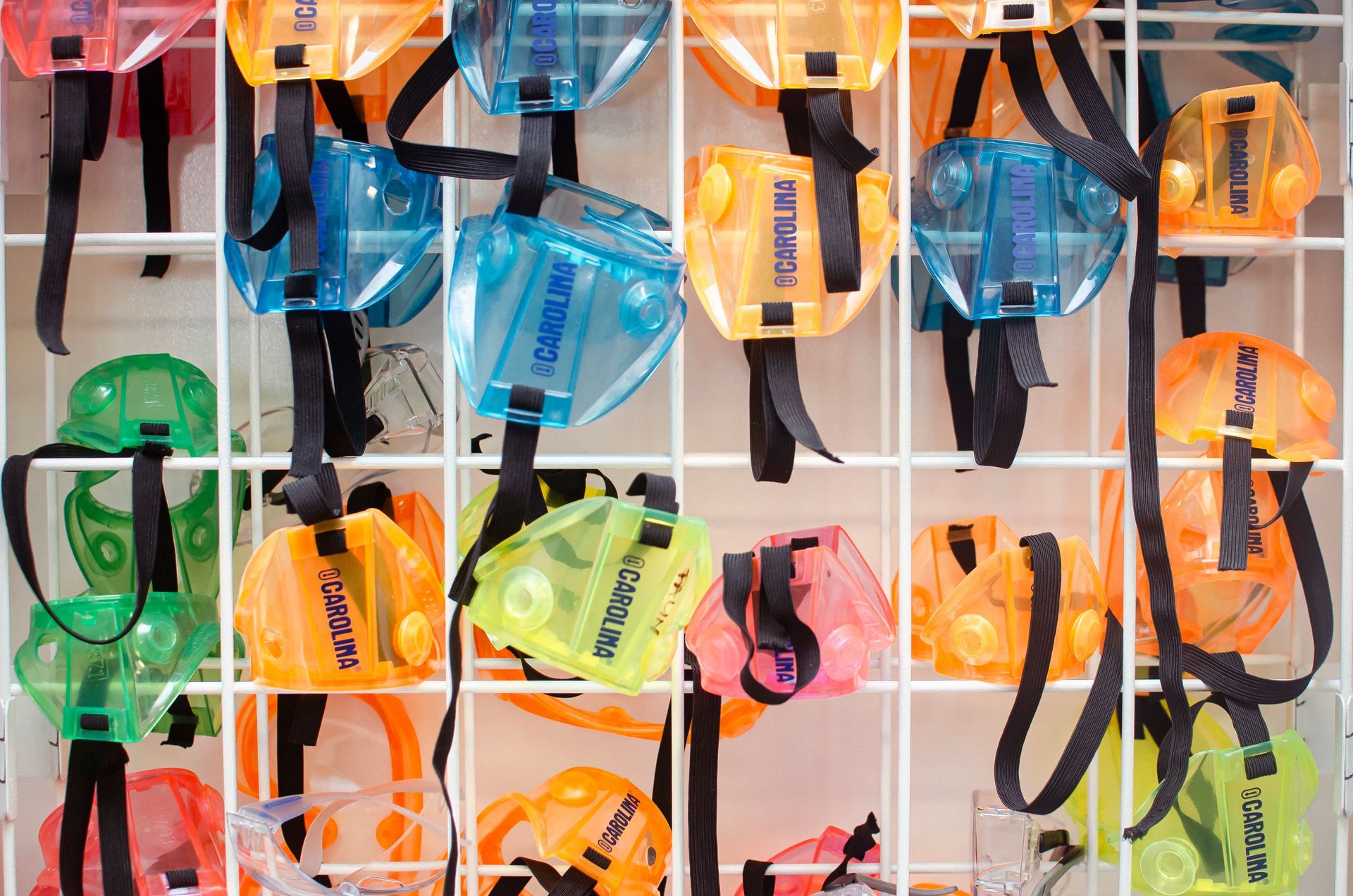 Rows of colorful, transparent dive lights hanging on a white grid display.