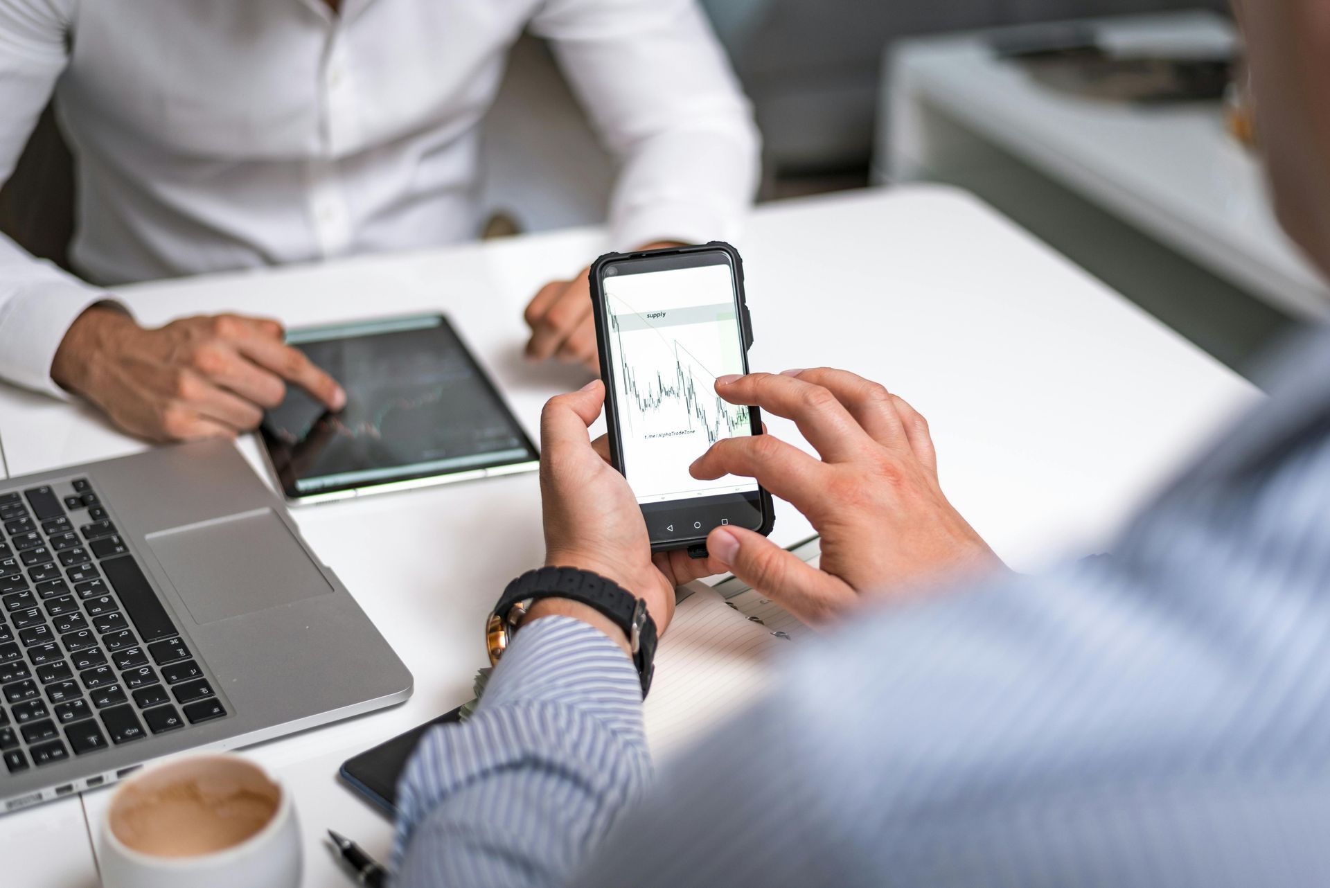 Dos personas en una mesa: una usa un teléfono y la otra una tableta.