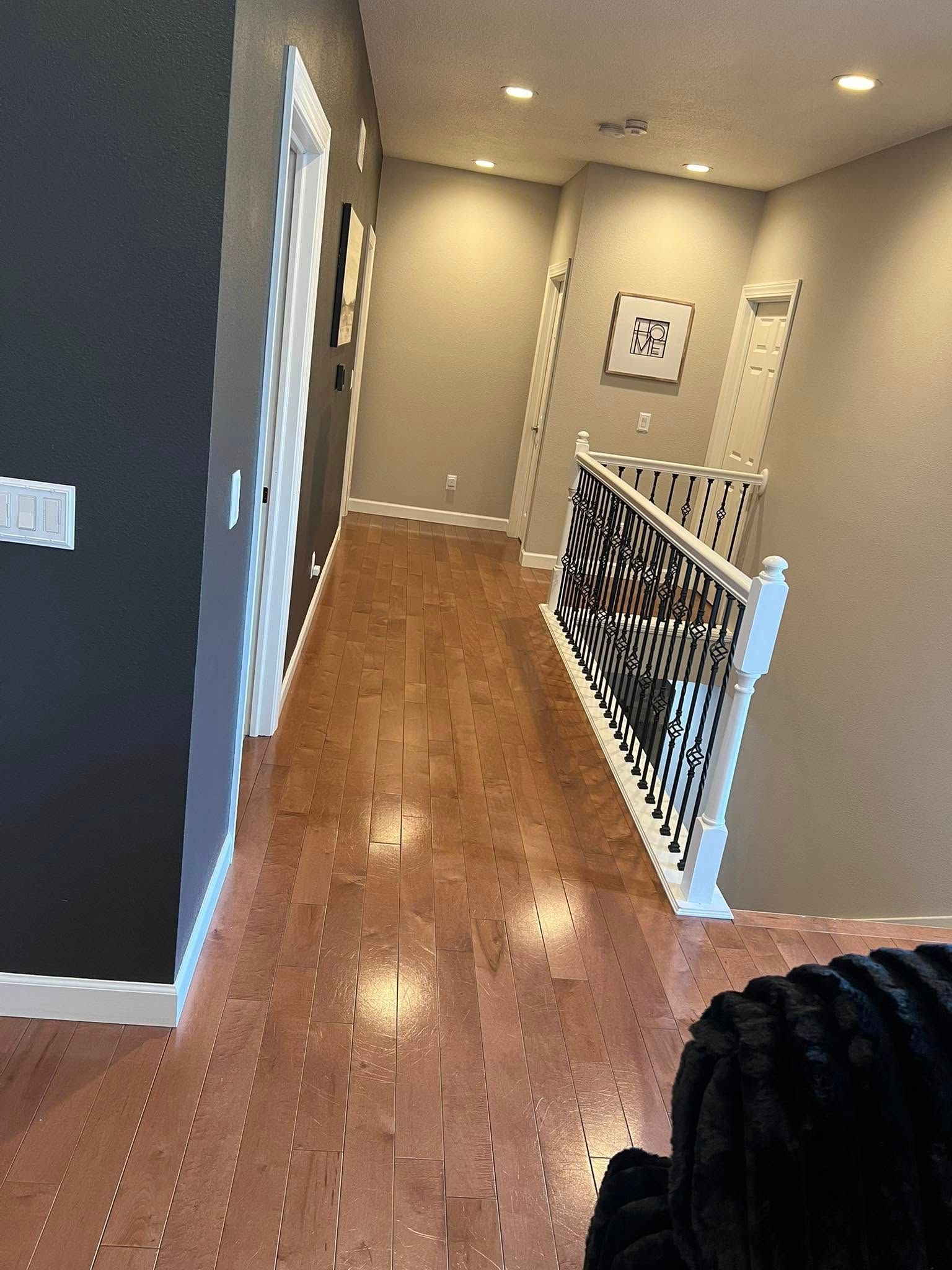 Hallway with hardwood floor, beige walls, white railing, and recessed ceiling lights