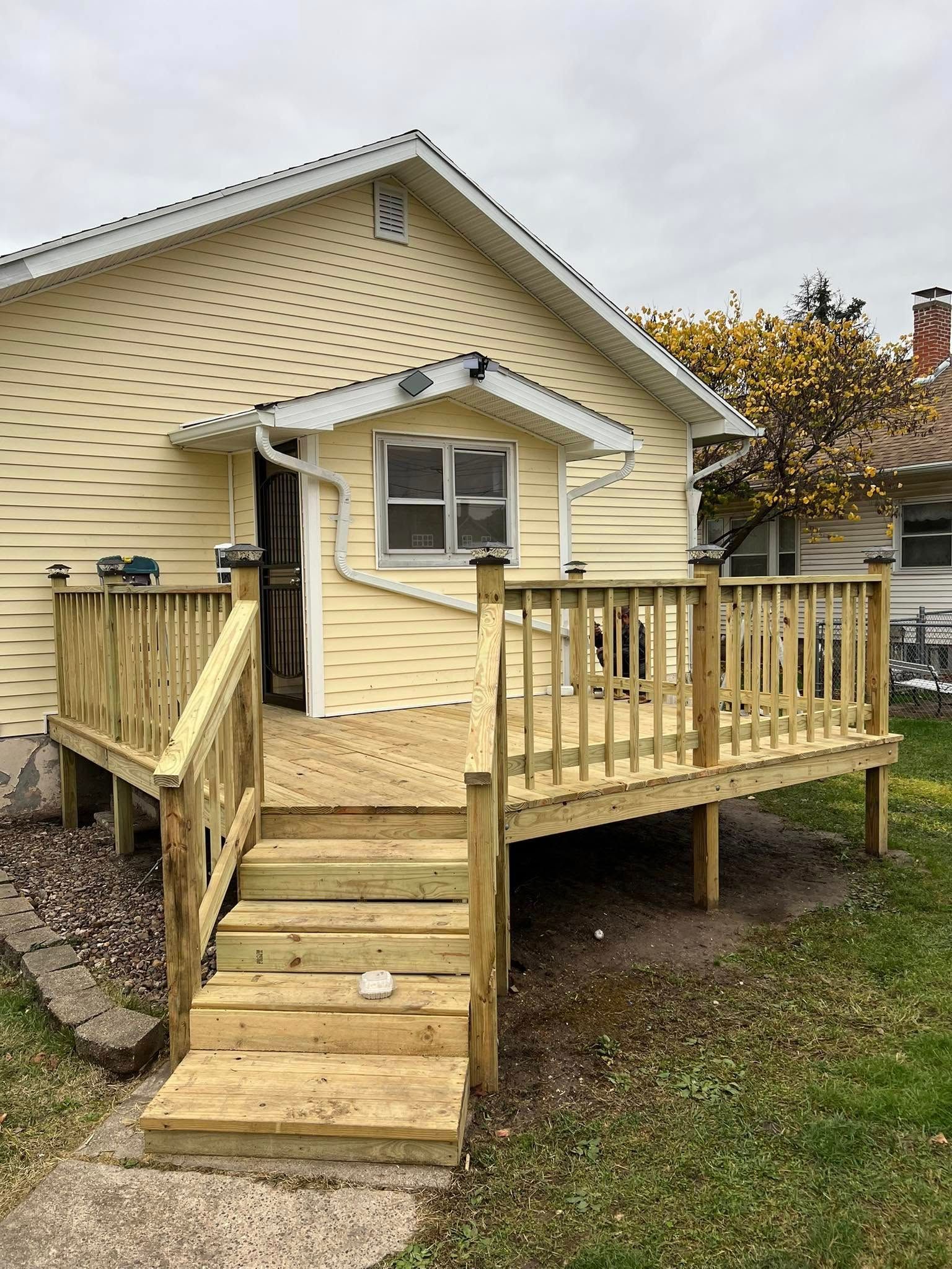 Wooden ramp and steps leading to a beige house entrance with a small porch and railing