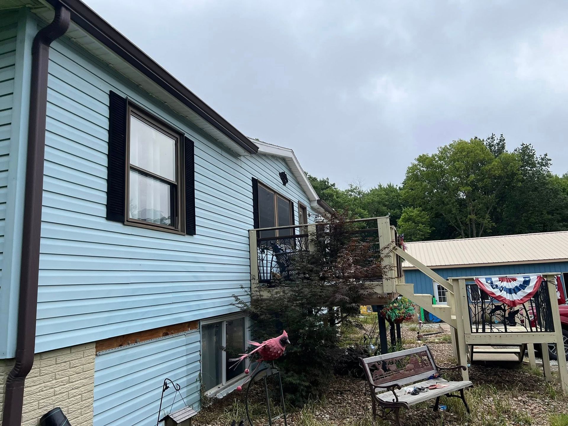 Blue house exterior with a small porch, stairs, and patriotic bunting under cloudy skies