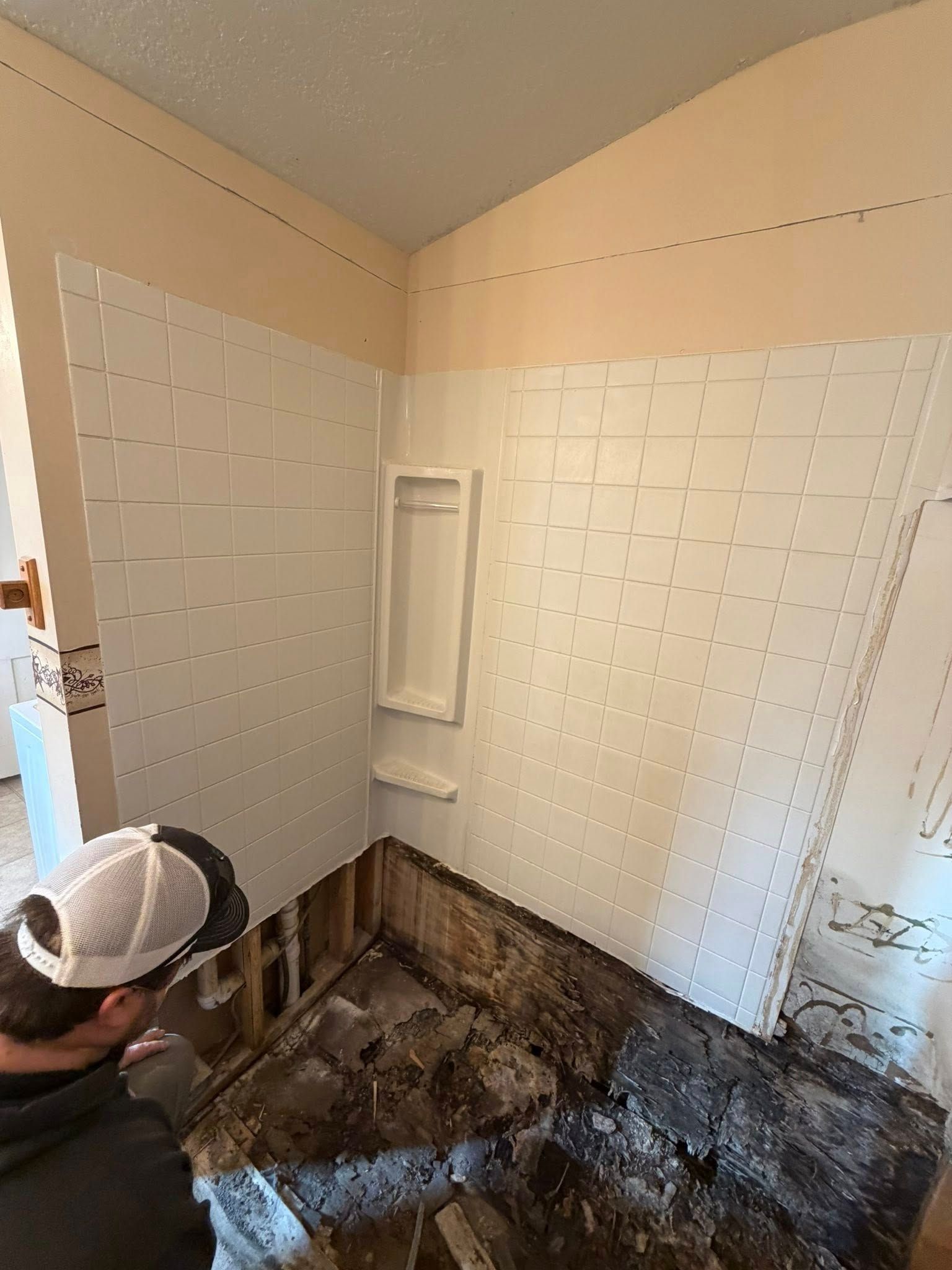 Worker removing a tiled shower floor during bathroom demolition