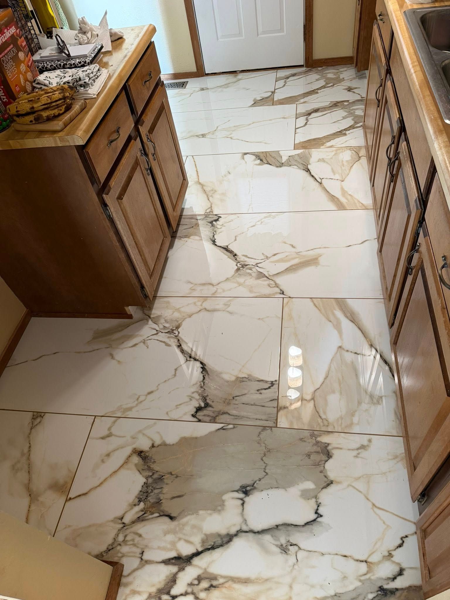 Kitchen hallway with glossy marble-pattern tile floor and wooden cabinets