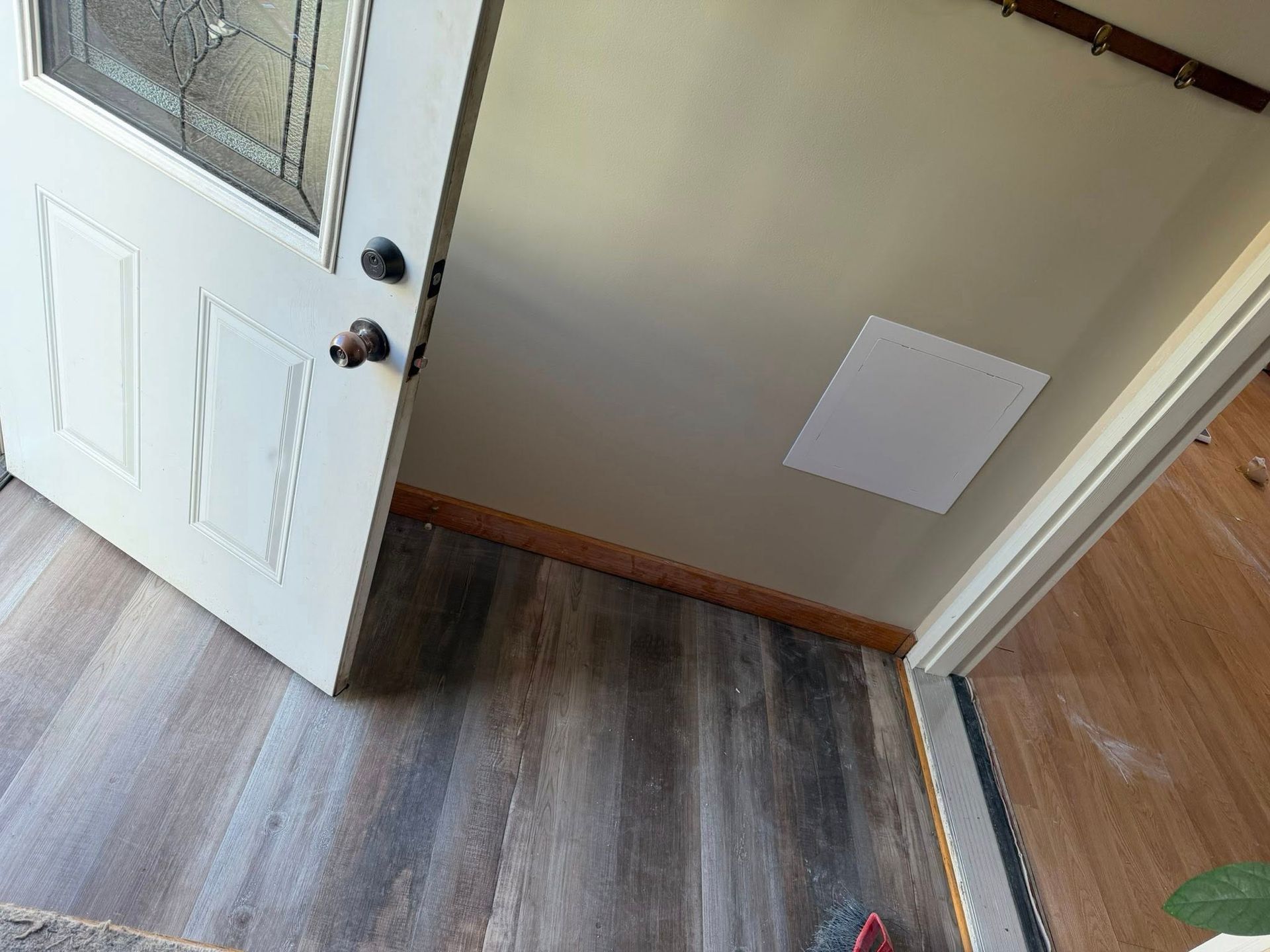 Open front door with white pet panel, gray wood floor, and a square wall vent near the entryway.