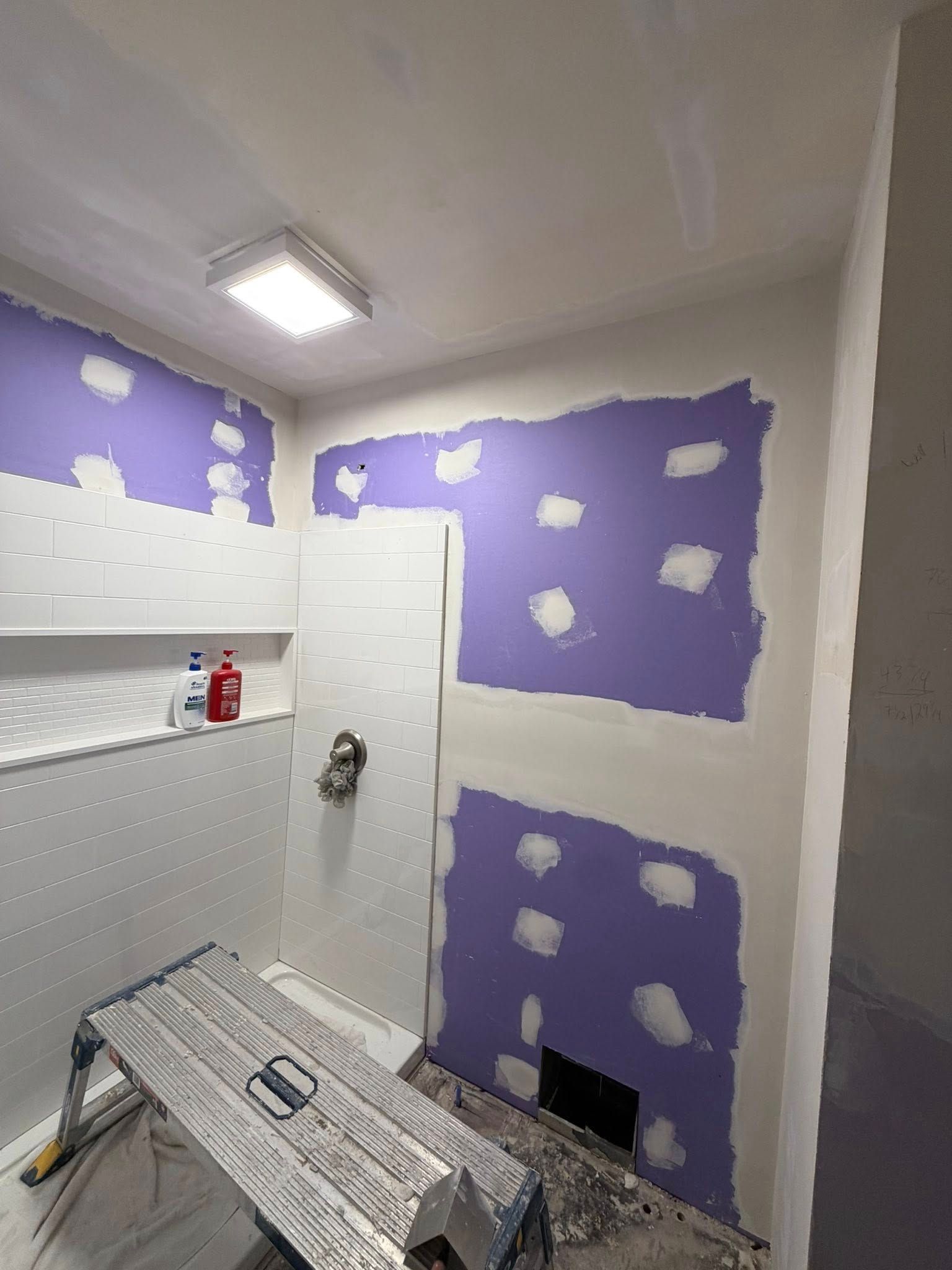 Purple-spackled bathroom walls, a white door, and a covered floor in a small renovation space.
