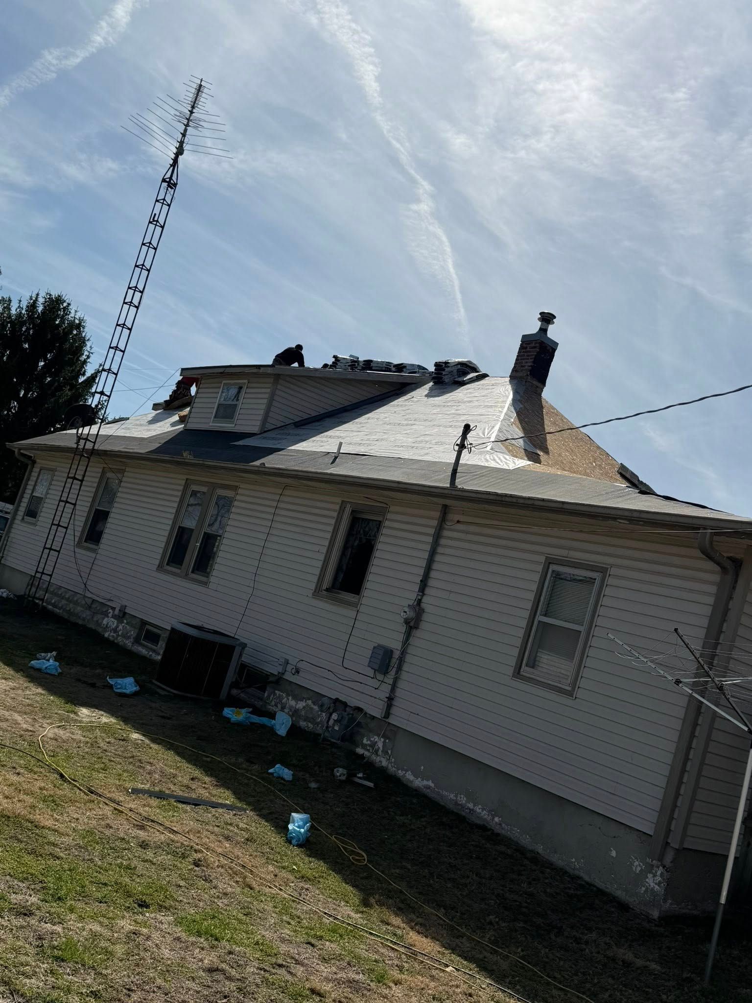 House roof with visible damage and a damaged antenna under a cloudy sky