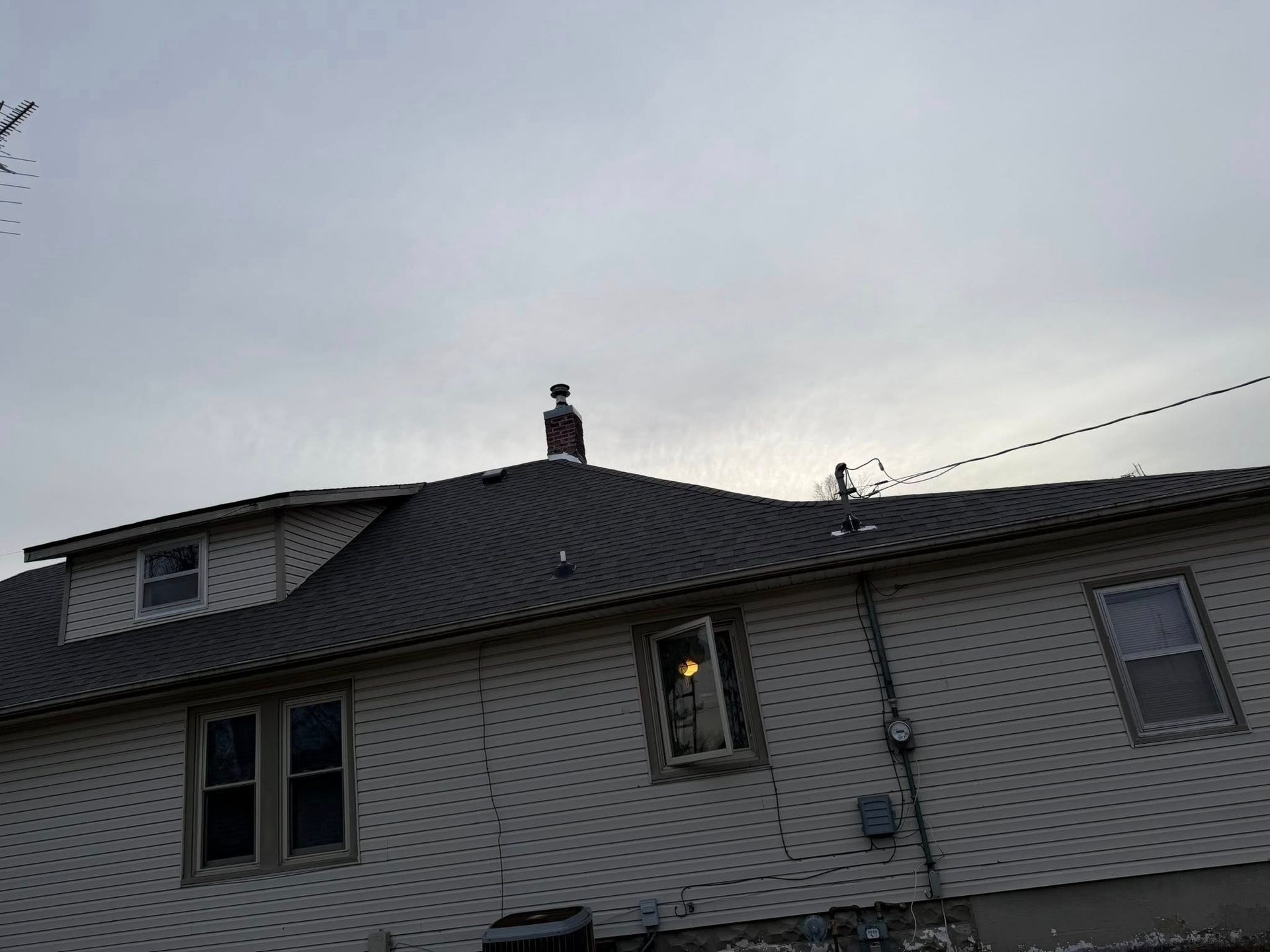 House roof with a small figure standing on top at dusk