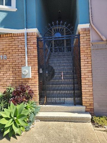 A brick building with a wrought iron gate and stairs leading up to it.