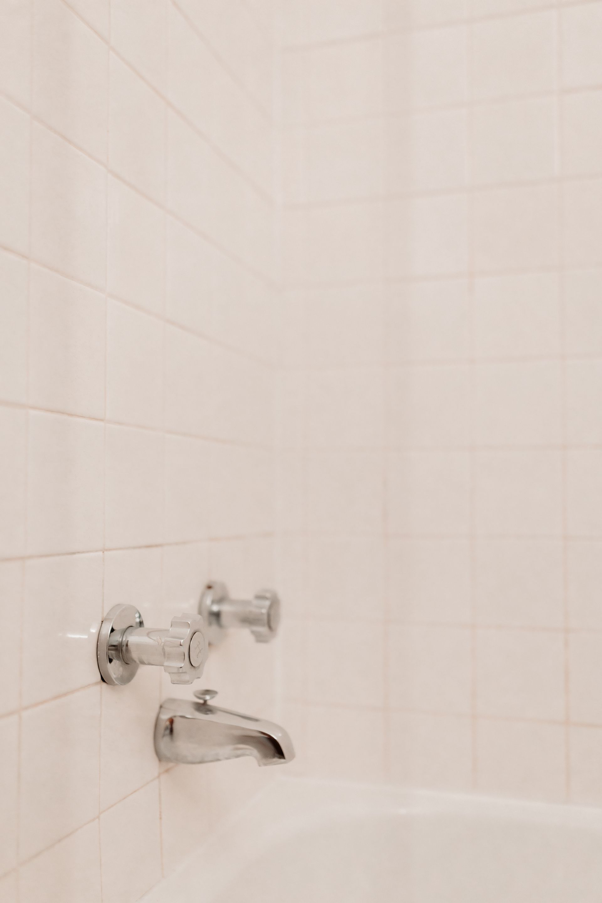 White tiled shower with vintage temperature knobs and white grout. Apartment in Northeast Minneapolis by RightMove Properties. 