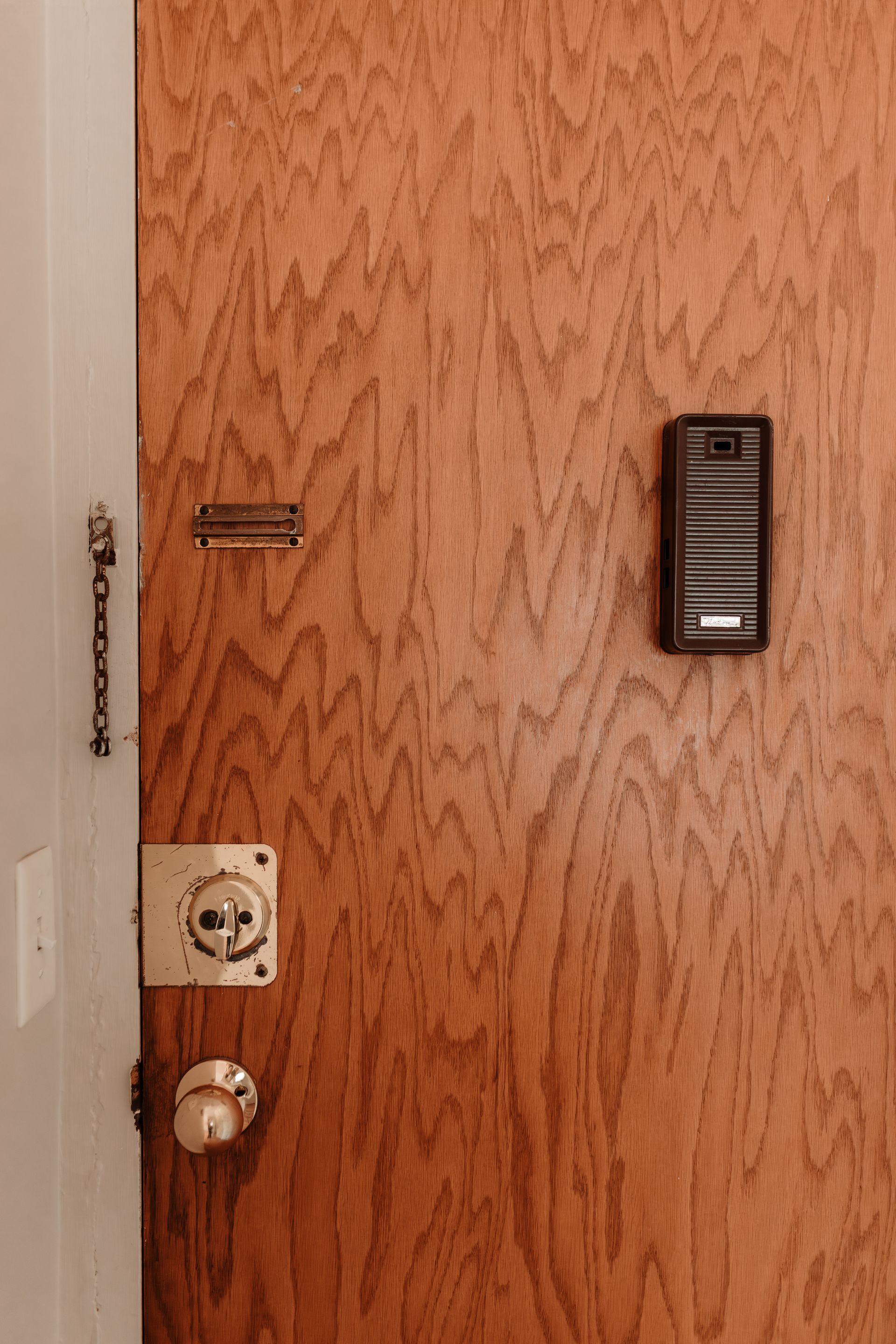 Wooden door with old fashioned looking hole, chain lock, and deadlock. Apartment in Northeast Minneapolis by RightMove Properties. 