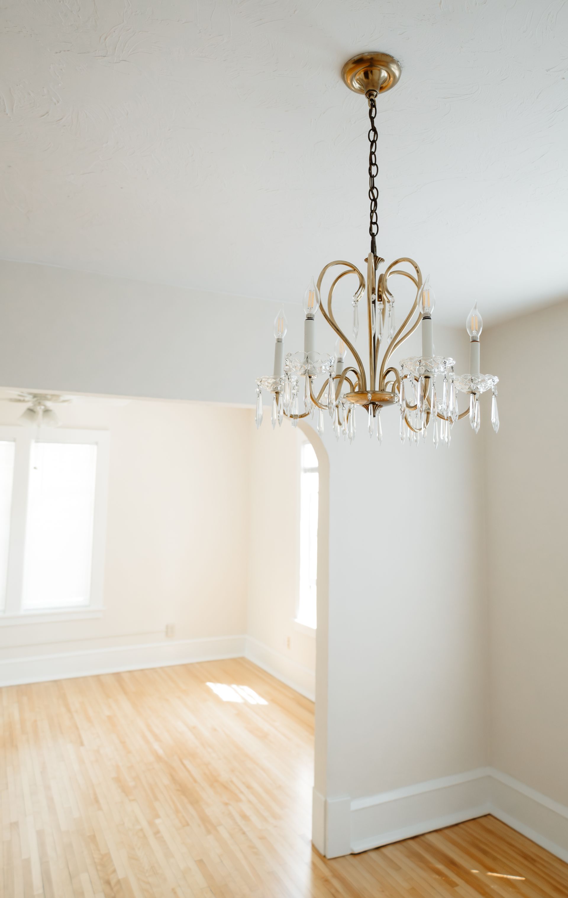 Close up if a teardrop glass and brass chandelier featuring digital candlesticks. Apartments in Linden Hills by RightMove Properties.