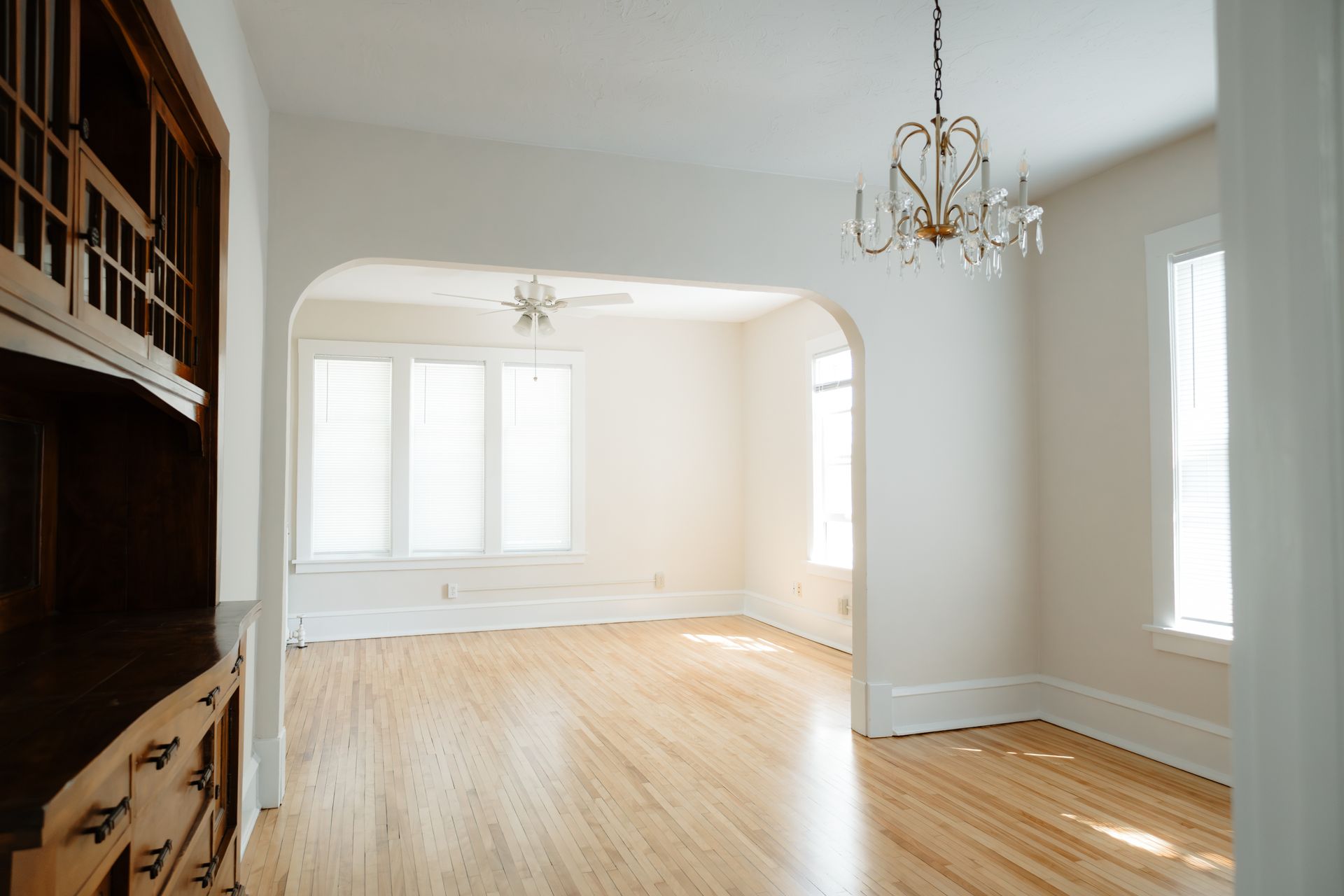 Hardwood floor in an open concept kitchen and living room. A vintage built in, chandelier, and large windows accent the space. Apartments in Linden Hills by RightMove Properties.