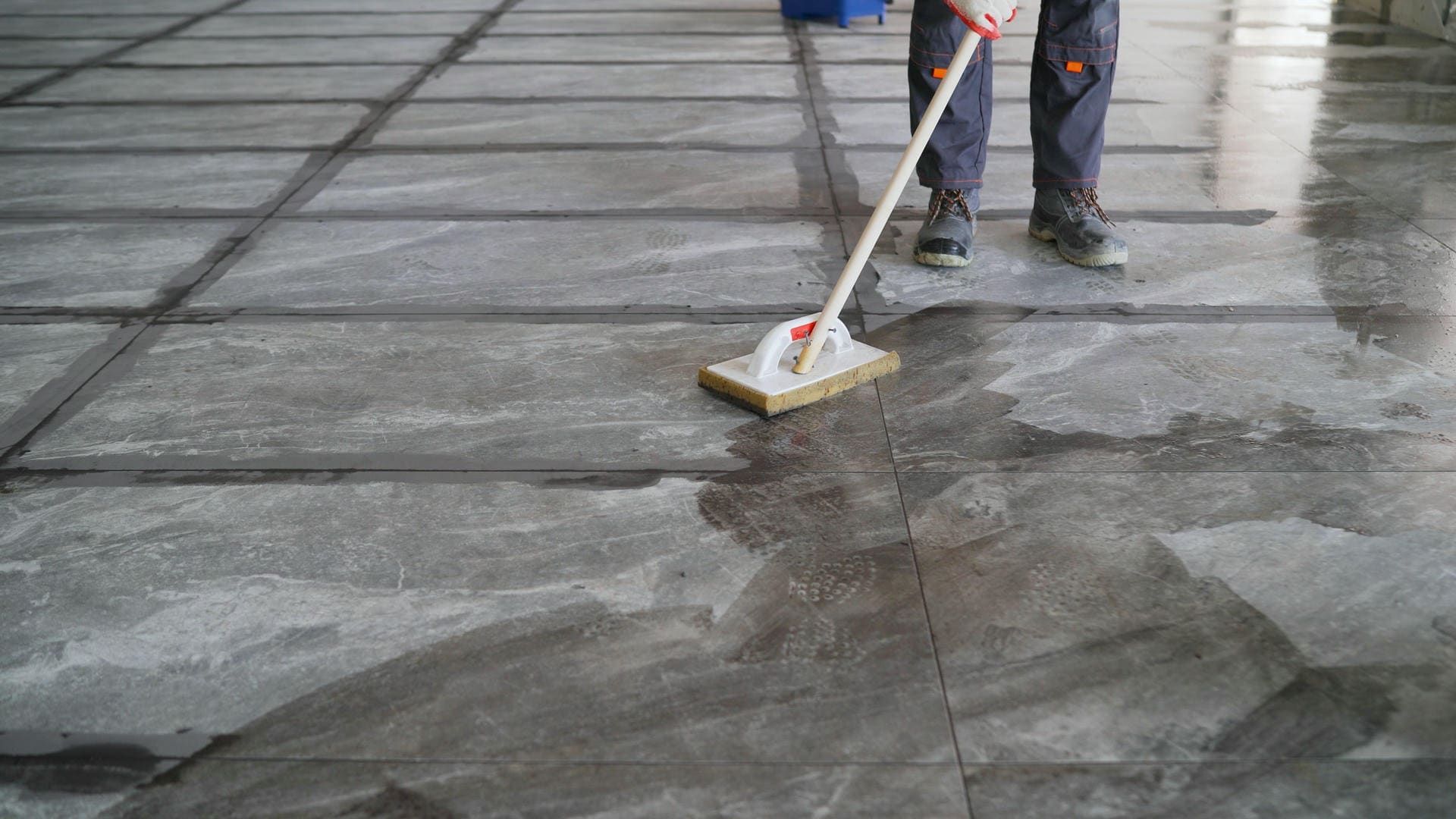 A person is cleaning a tiled floor with a mop.