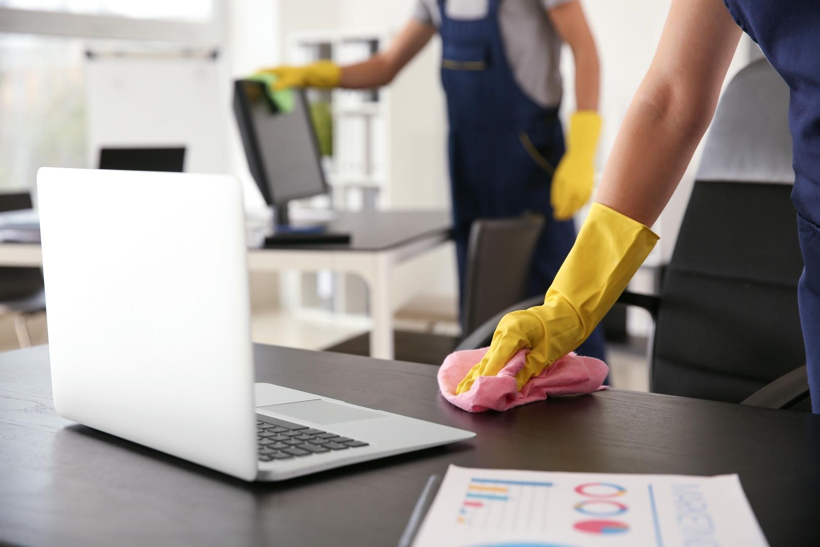 A person is cleaning a desk with a sponge in an office.