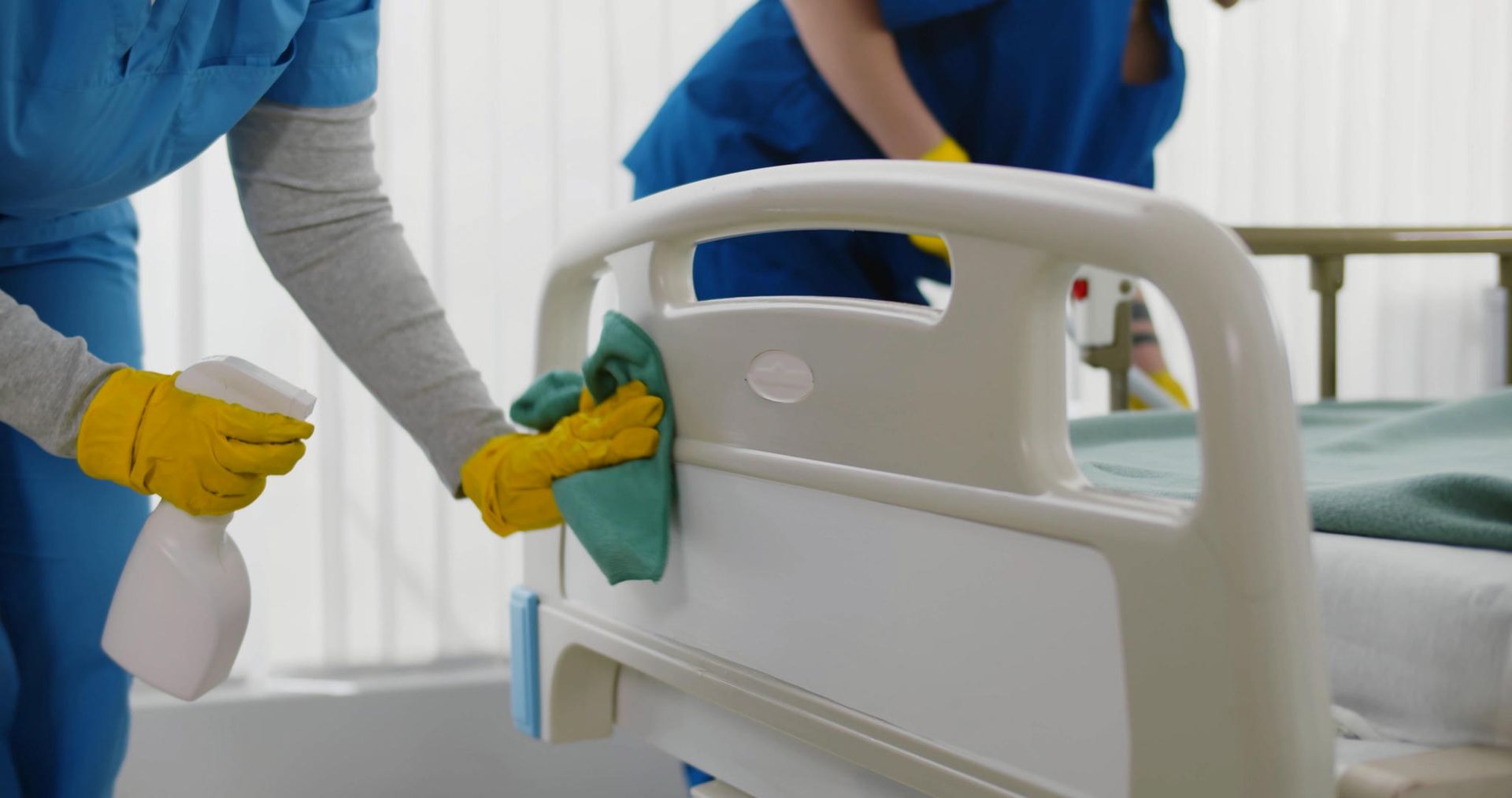 Two nurses are cleaning a hospital bed in a hospital room.