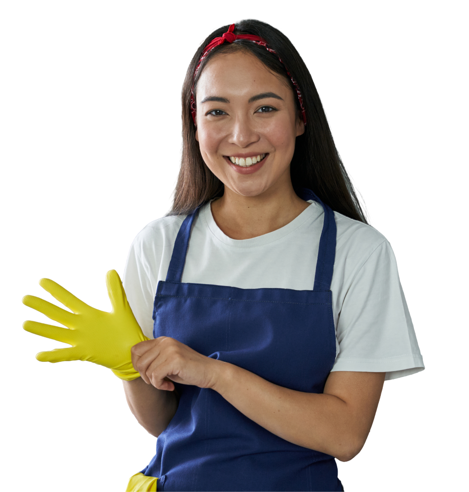A woman in an apron is putting on a yellow rubber glove.