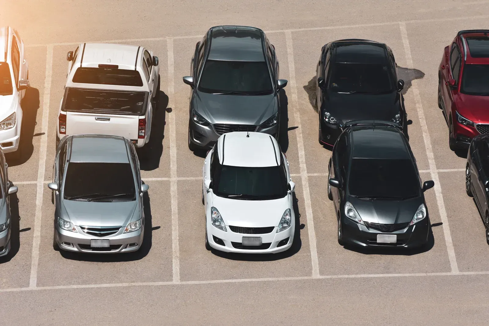 Cars parked in marked spaces in an outdoor parking lot.