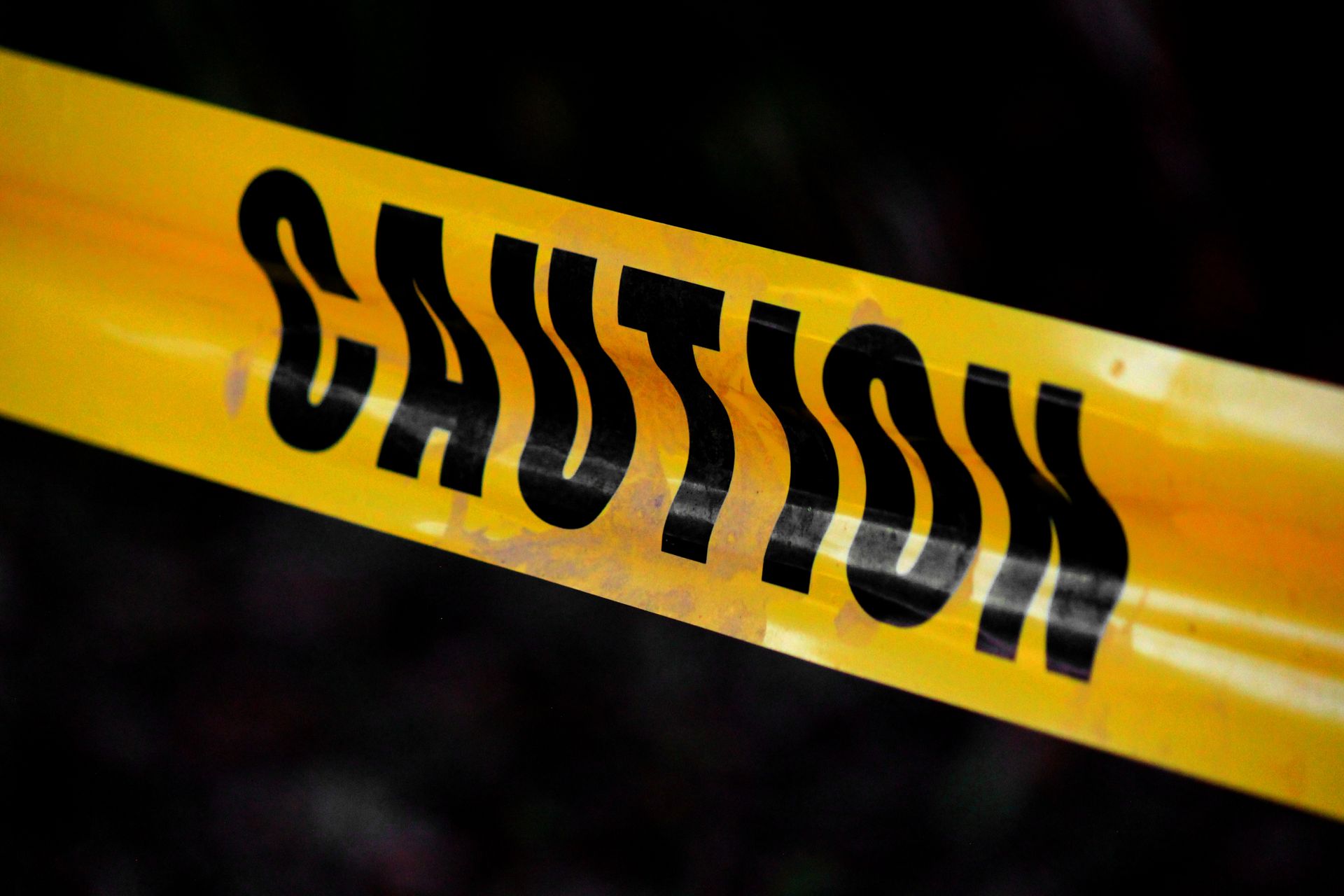 Yellow caution tape with bold black warning text diagonally across a dark background