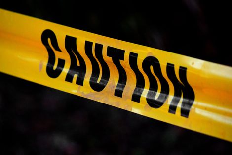 Yellow caution tape with bold black warning text diagonally across a dark background