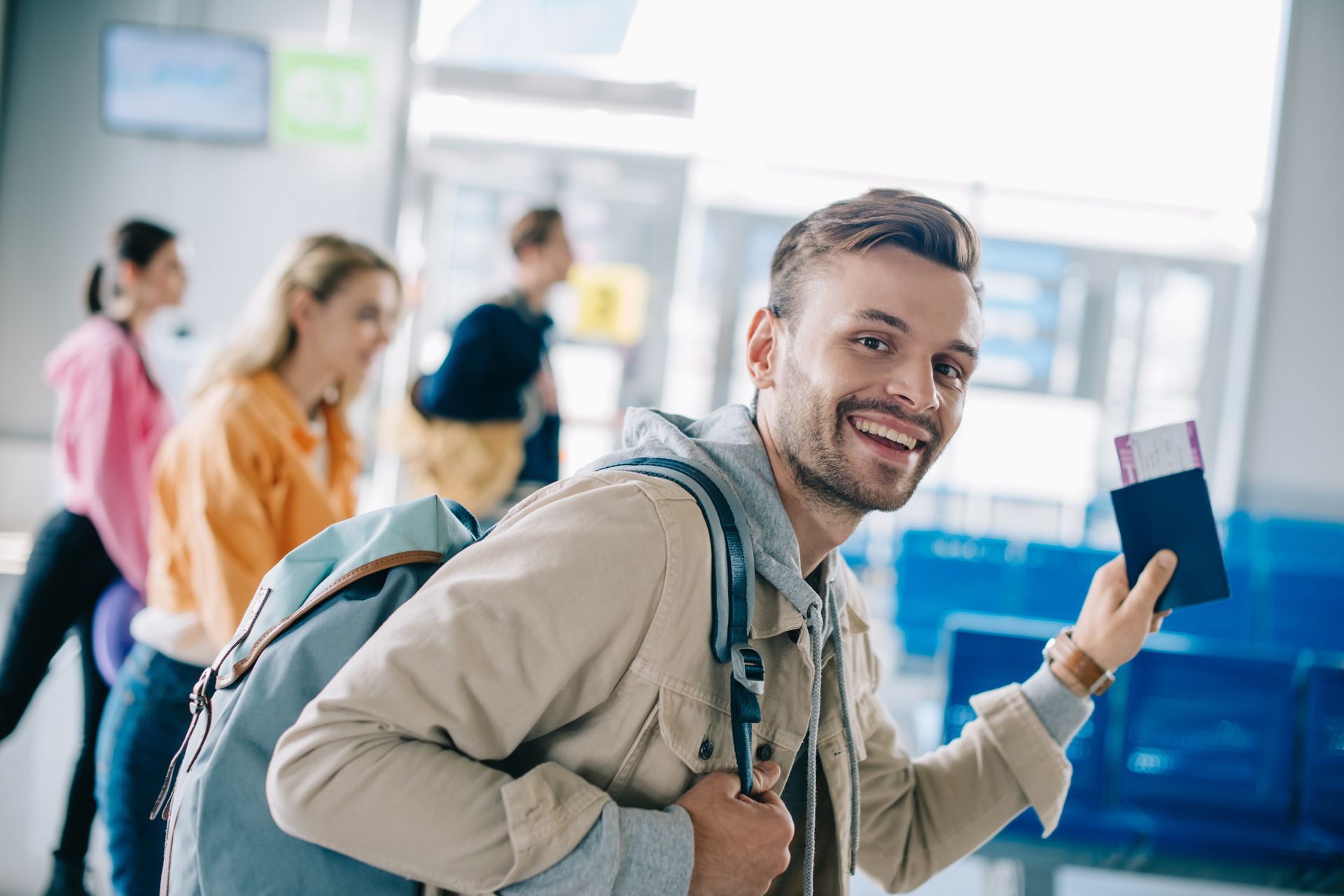 Traveler smiling with a backpack and passport at an airport check-in counter