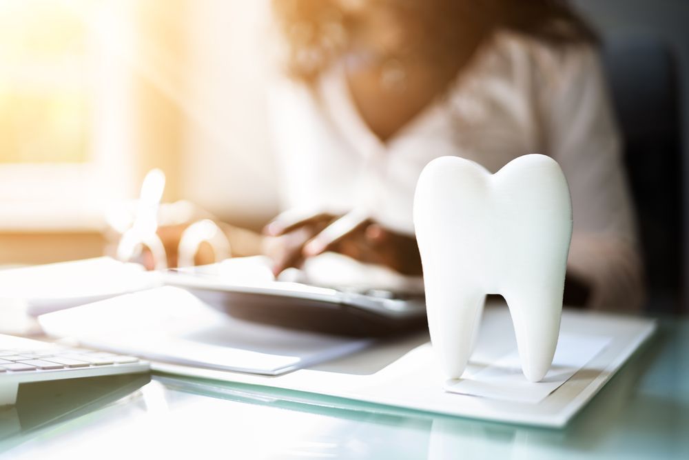 A woman is sitting at a desk with a tooth on it.