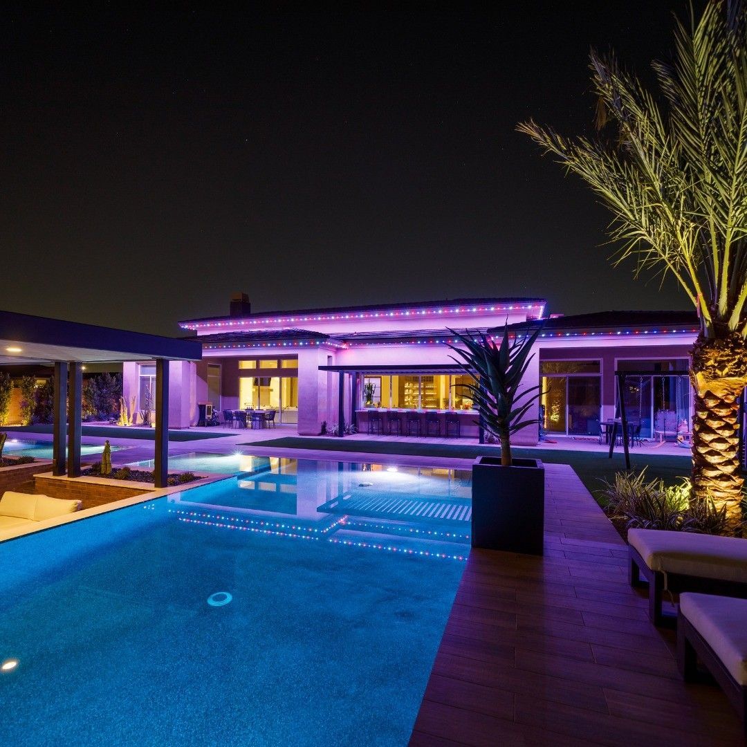Modern villa pool at night with purple lights and palm trees
