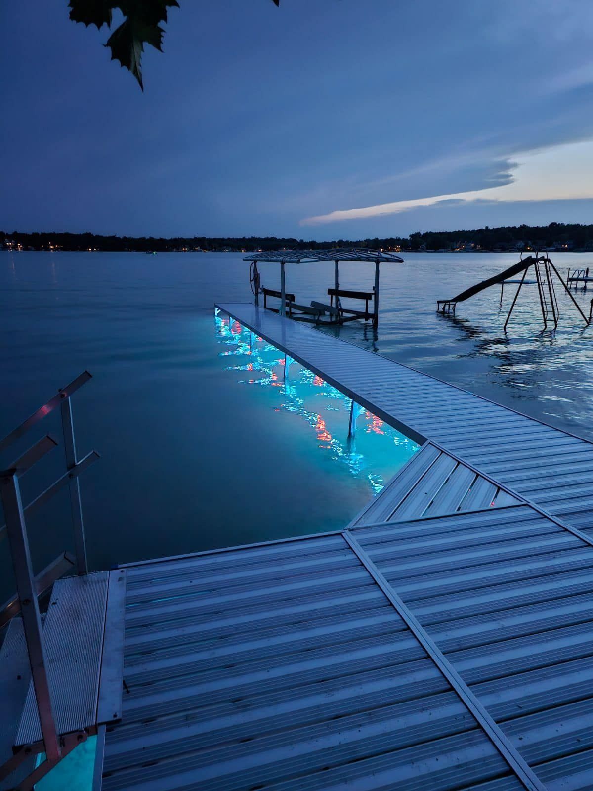Blue-lit lakeside dock with stairs and railings at dusk