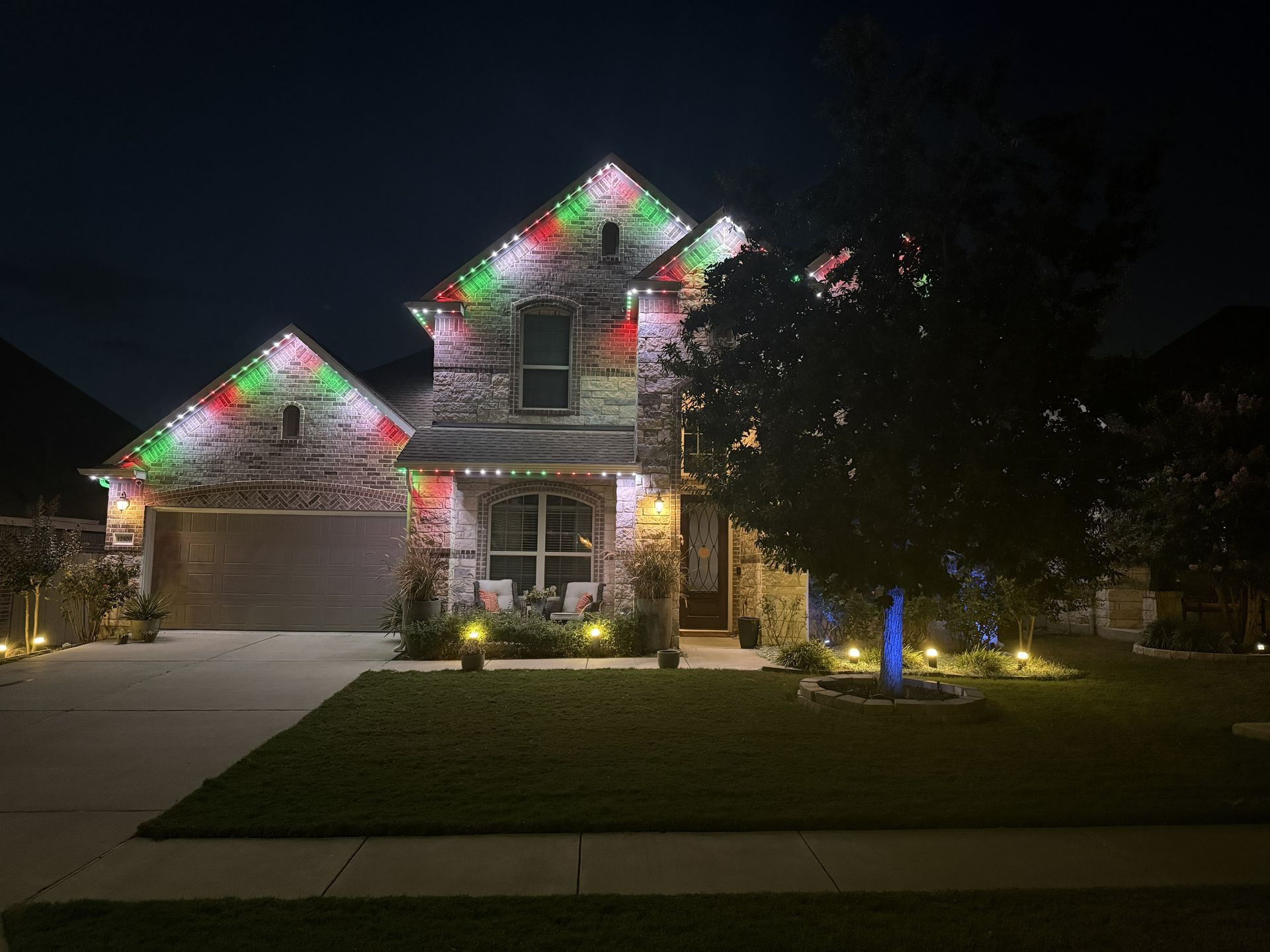 Nighttime suburban house decorated with colorful Christmas lights and a lit lawn ornament