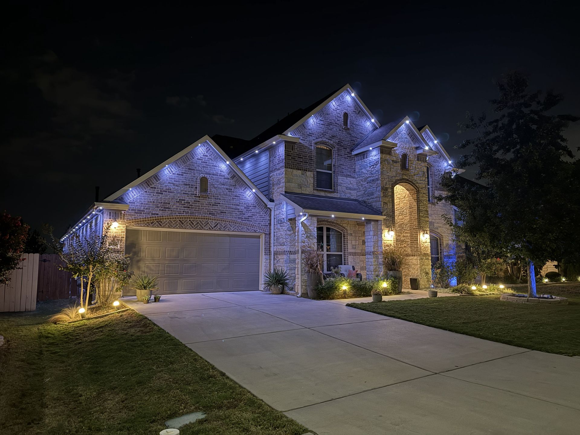 Suburban house at night with blue roof lights and warm front porch lighting