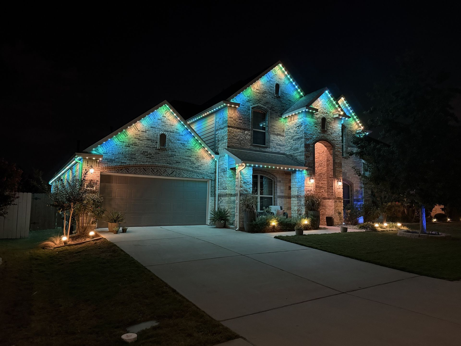 Suburban house at night with colorful roof lights and a lit driveway