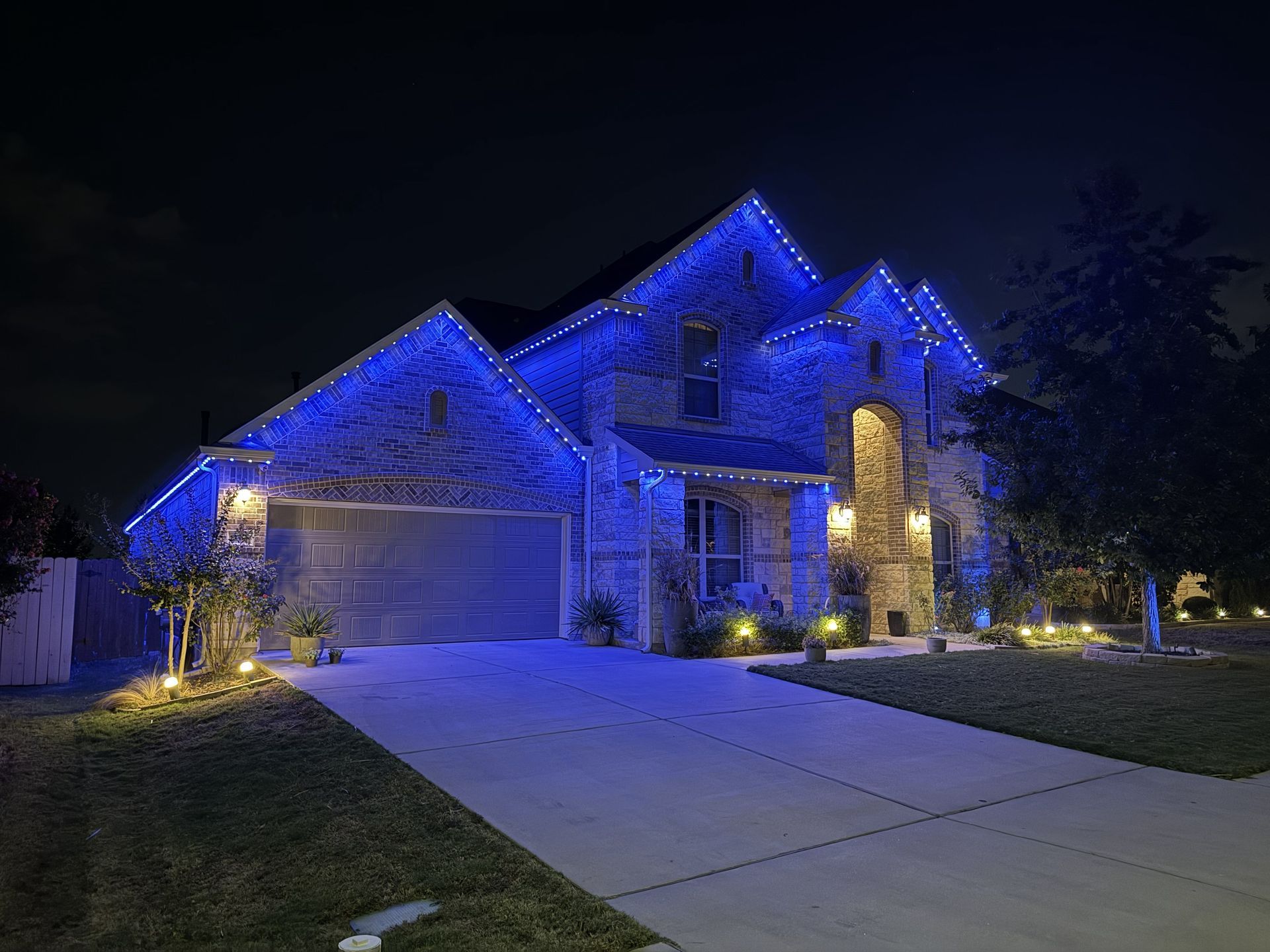 Blue-lit suburban house at night with a driveway and garage