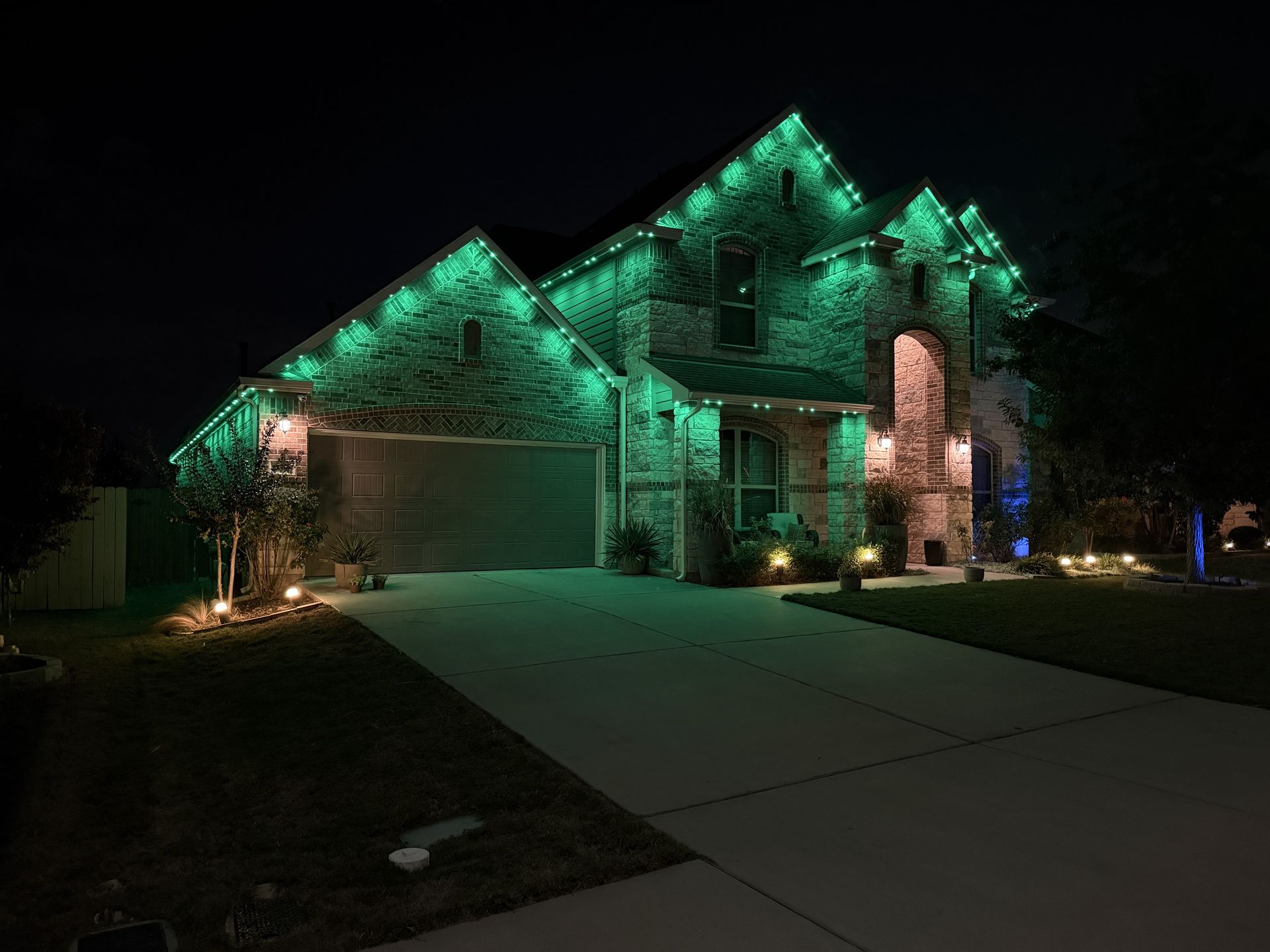 Suburban house at night with green and blue decorative exterior lighting