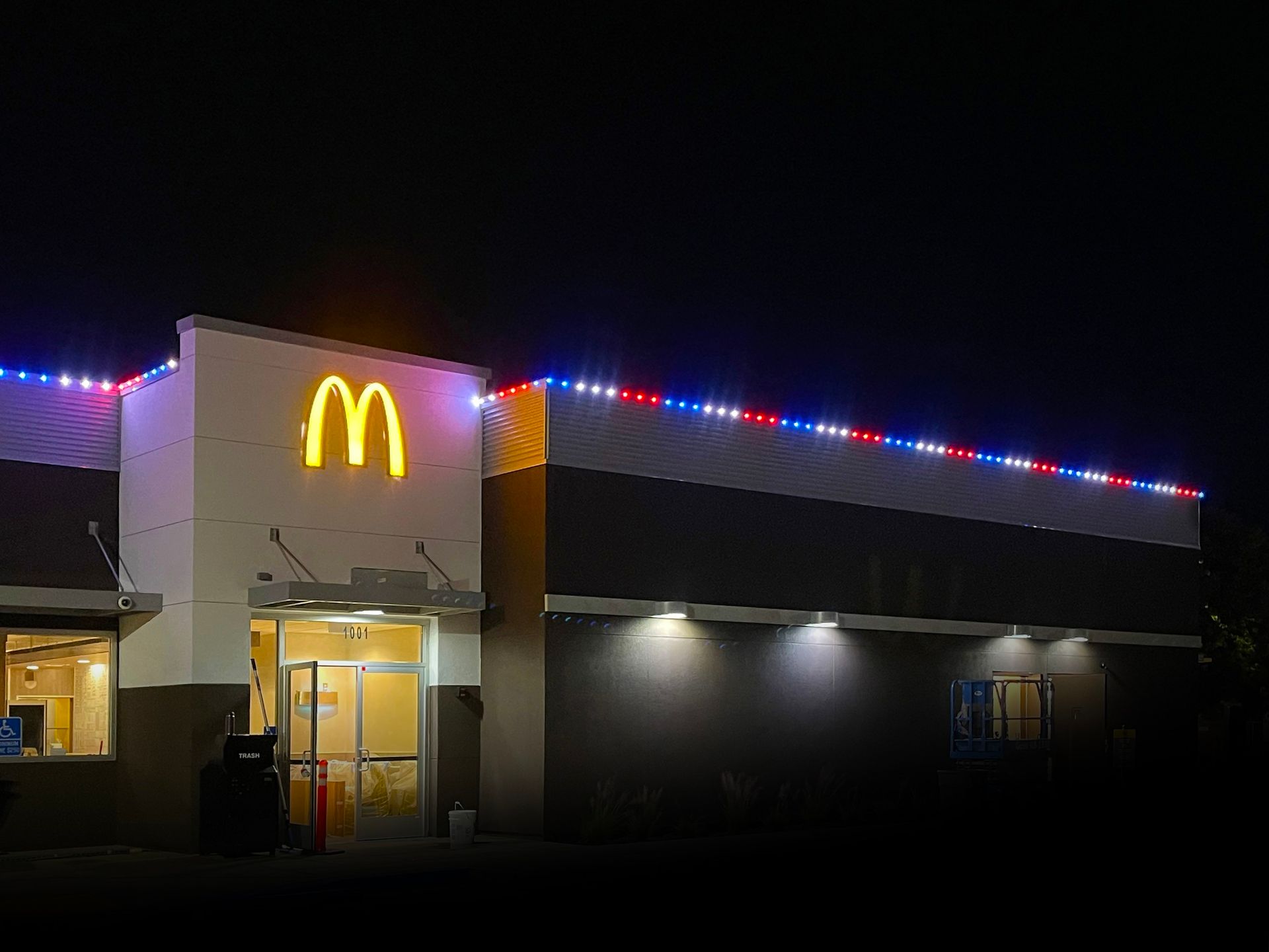 McDonald’s restaurant at night with glowing golden arches and red, white, and blue roof lights