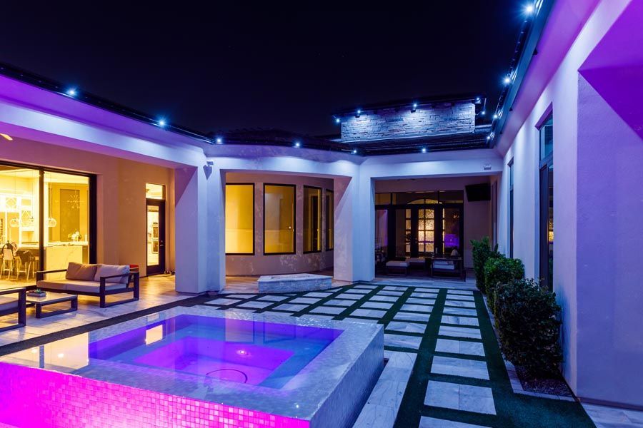 Modern patio with lit pool and purple-blue ambient lighting at night