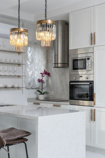 Modern white kitchen with marble island, hanging pendant lights, and built-in appliances