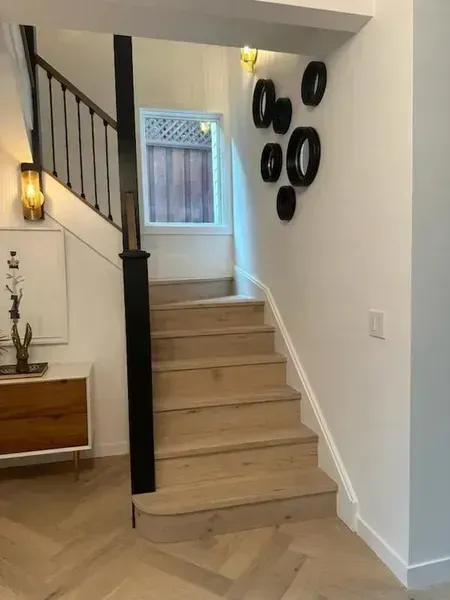 Indoor staircase with beige steps, black railing, and framed wall decor in a bright entryway